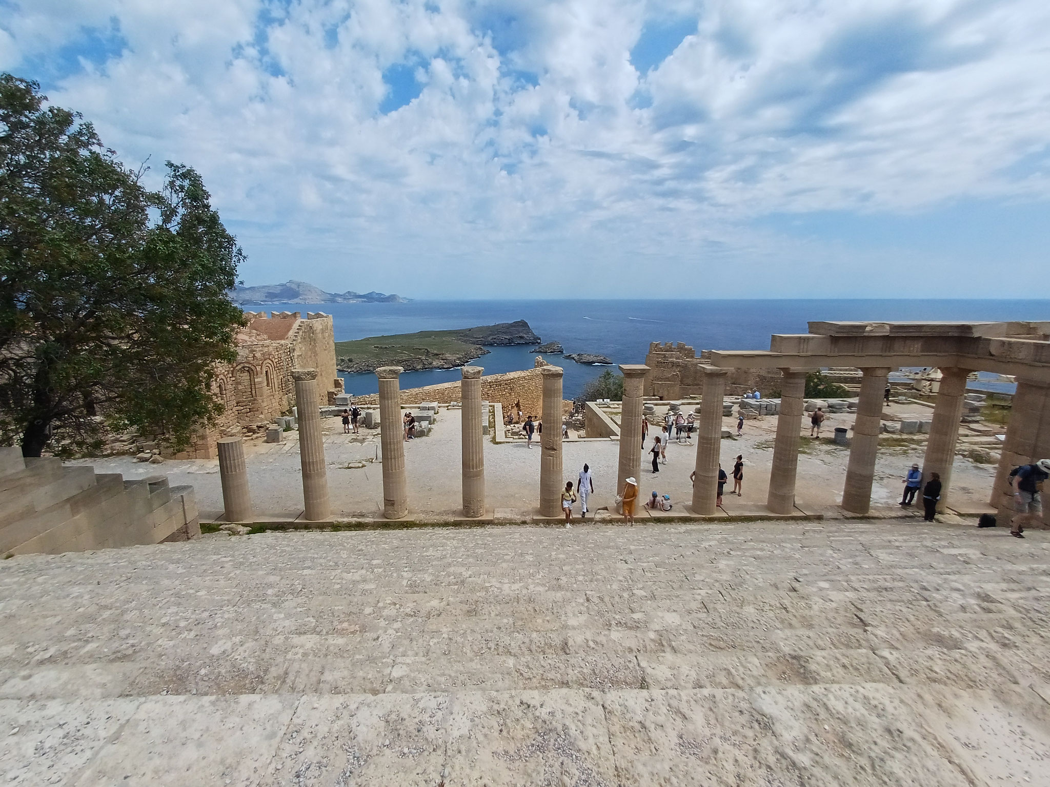 Eine sehr hohe Treppe die hinauf zum höchsten Punkt der Akropolis führt. die Treppe wurde von oben fotografiert. Im Hintergrund der Treppe sind Säulen aneinandergereiht.