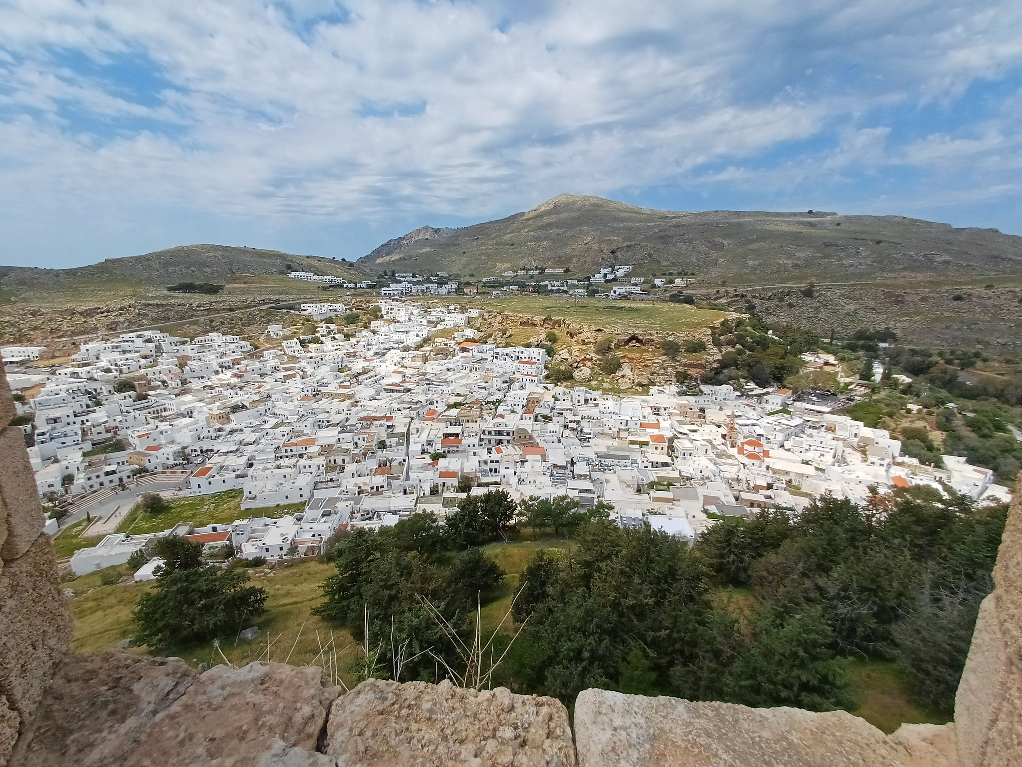 Im Hintergrund erstrecken sich die weißen Häuser von Lindos. Das Foto ist von oben fotografiert.