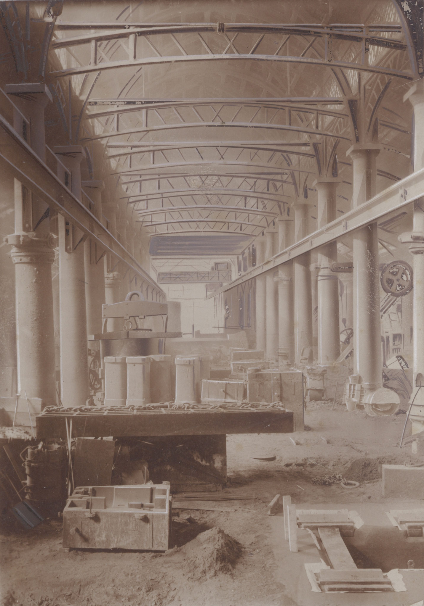 Foto der Gießhalle, um 1922, mit einem späteren Laufkran, der an den Säulen befestigt war. Vorne rechts ist ein Gussteil zu erkennen, das direkt im Sand im Boden gegossen wurde.