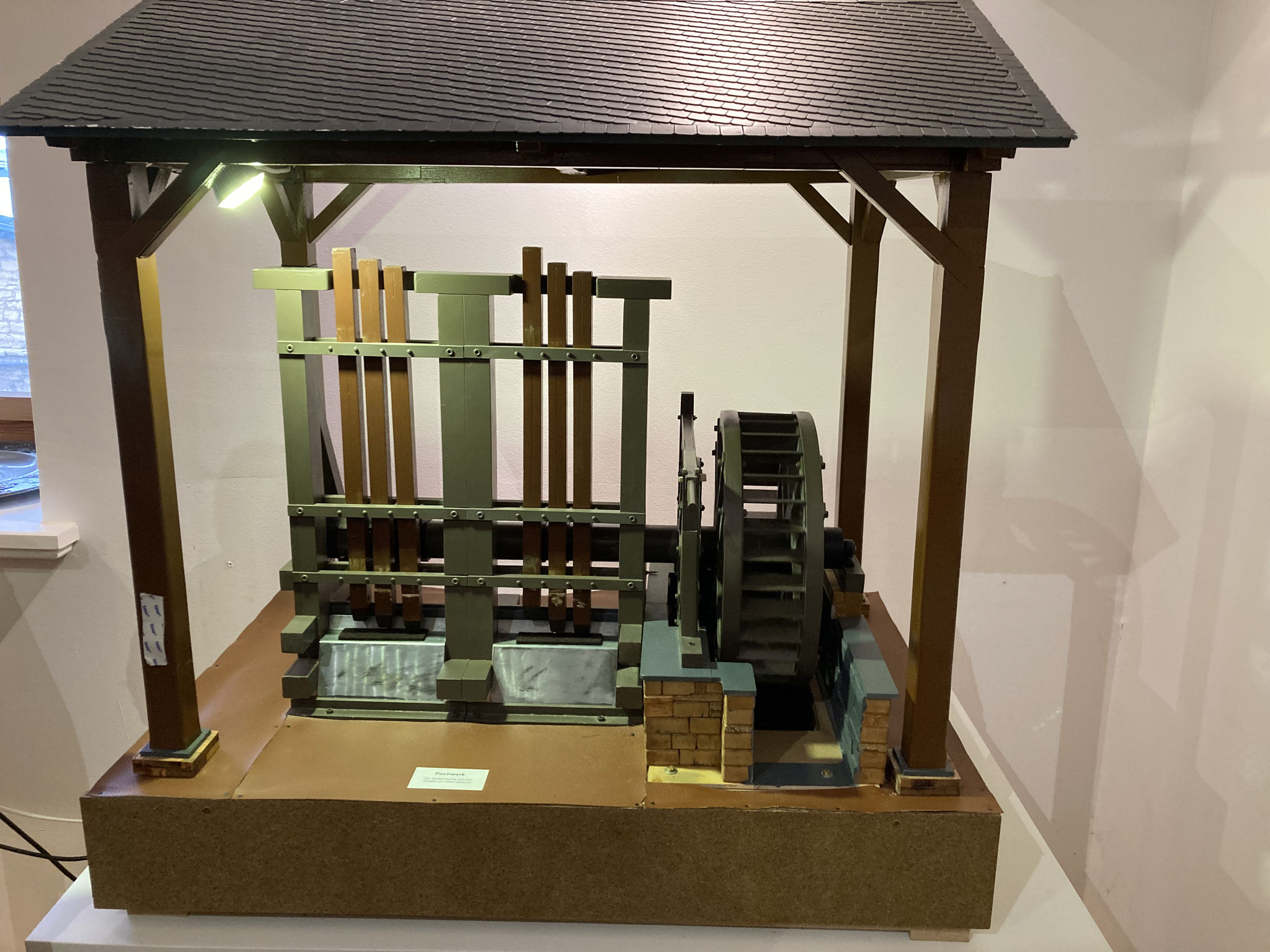 Model of a crusher with six wooden stamps crushing rock and slag, driven by a water wheel.