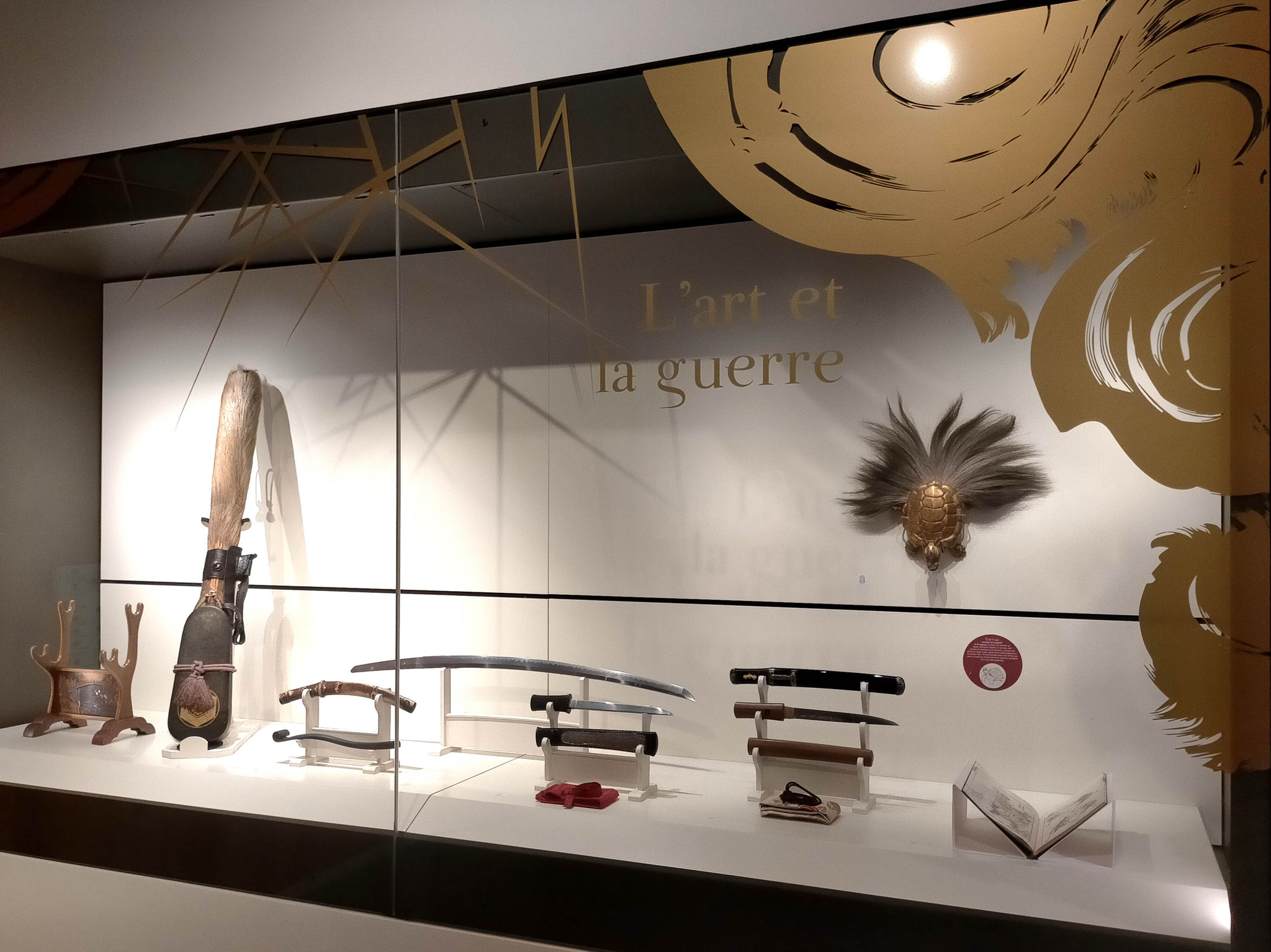 Vitrine des armes. Adhésif doré, découpe numérique. Exposition "Japon. Archipel des arts", musée Crozatier