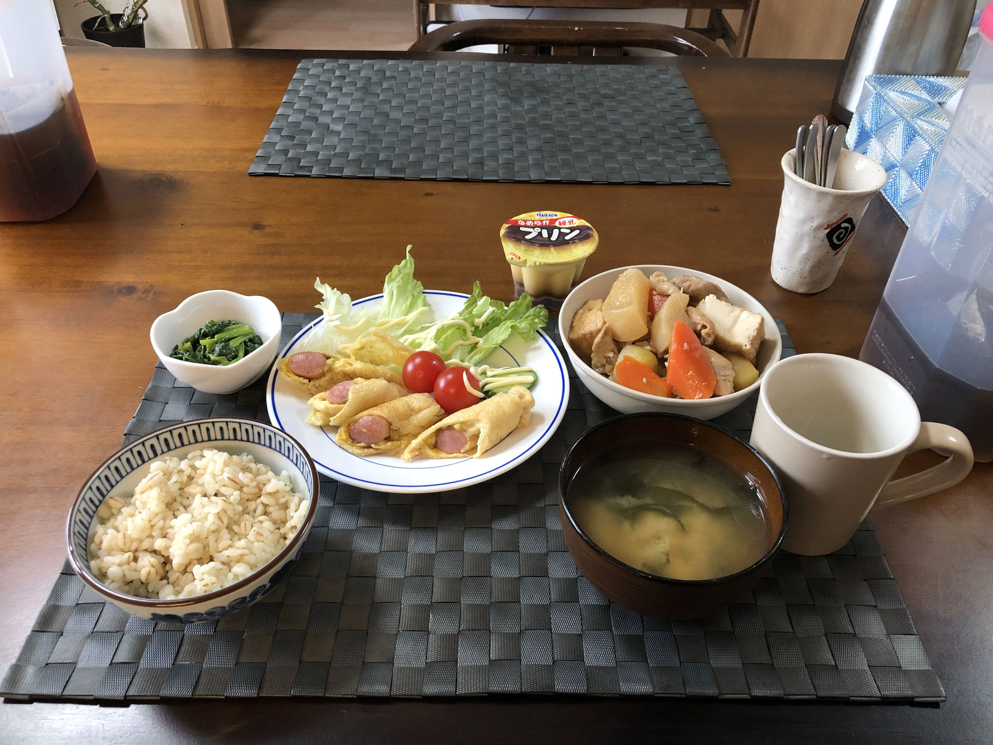 3月9日水曜日、Ohana朝食「大根と鳥肉の煮物、ウインナーとチーズの油揚げ巻き焼き（カレー味）、生野菜（レタス、プチトマト）ほうれん草の胡麻和え、みそ汁（豆腐、わかめ）、プリン」