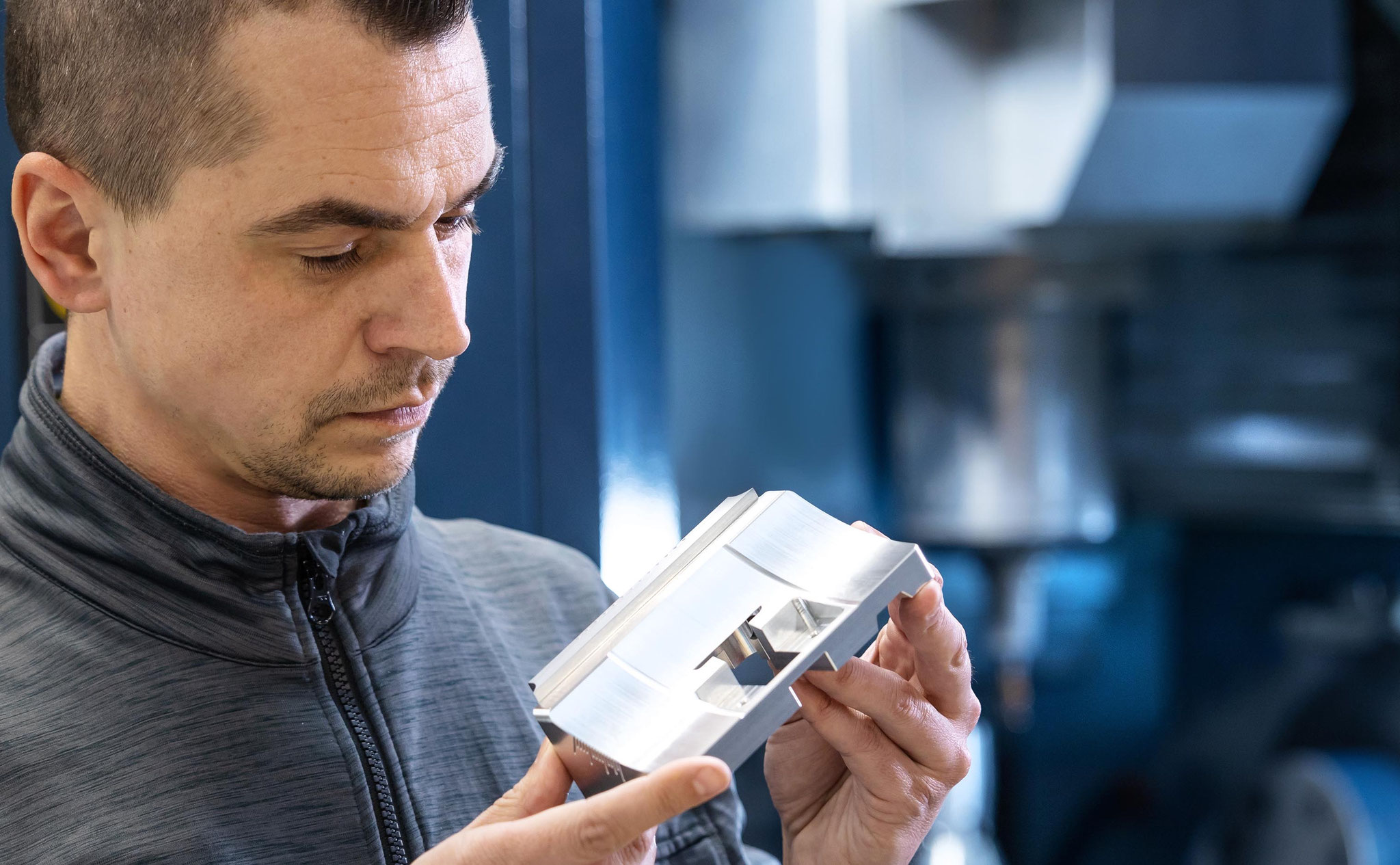 Werbefoto eines Mitarbeiters in der Produktion, der ein präzise gefrästes Metallteil prüft – industrielle Businessfotografie für Maschinenbau und Fertigungsunternehmen