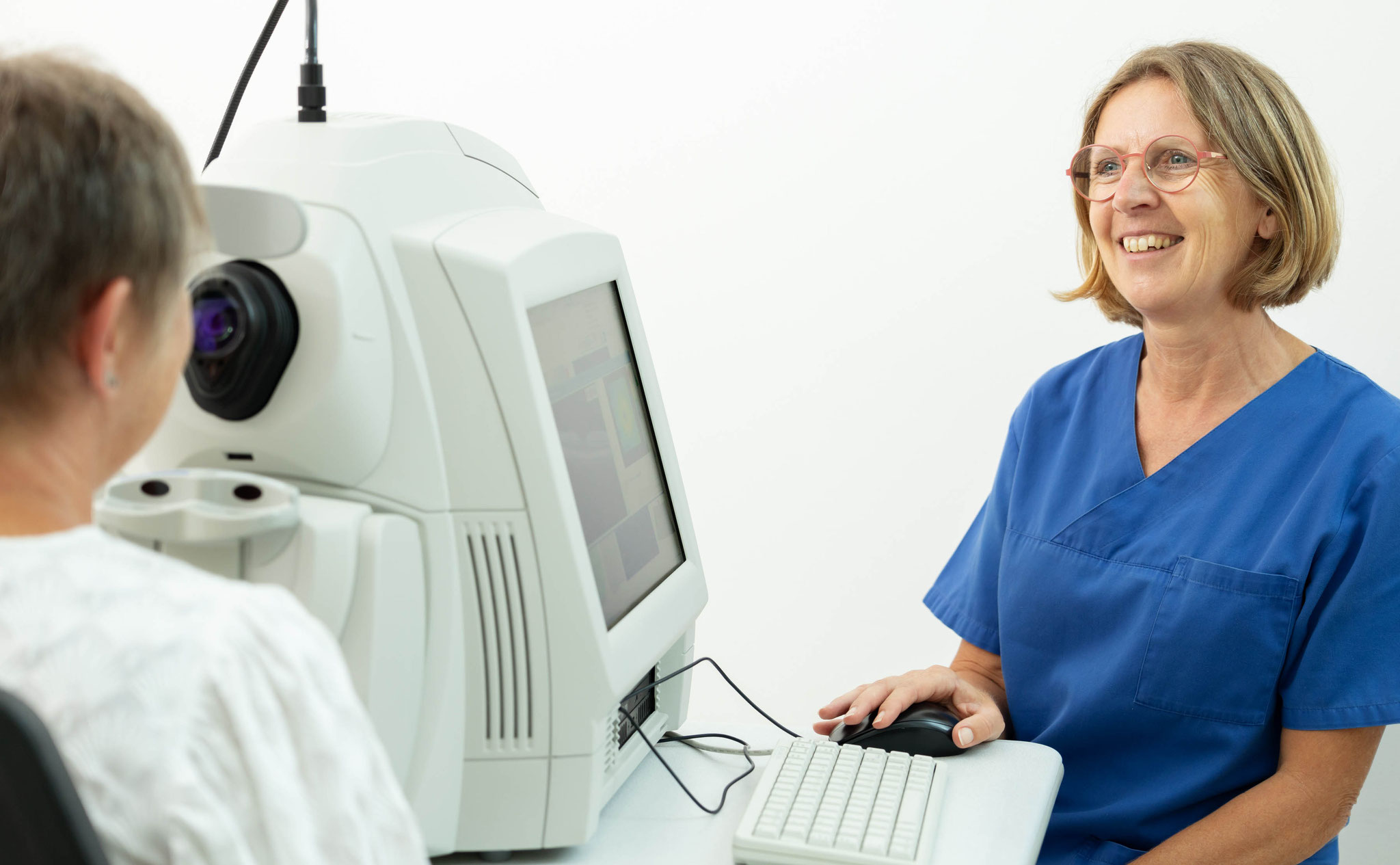 Sehtest mit moderner Augenmessung – Mitarbeiterin bedient Diagnostikgerät in Augenarztpraxis