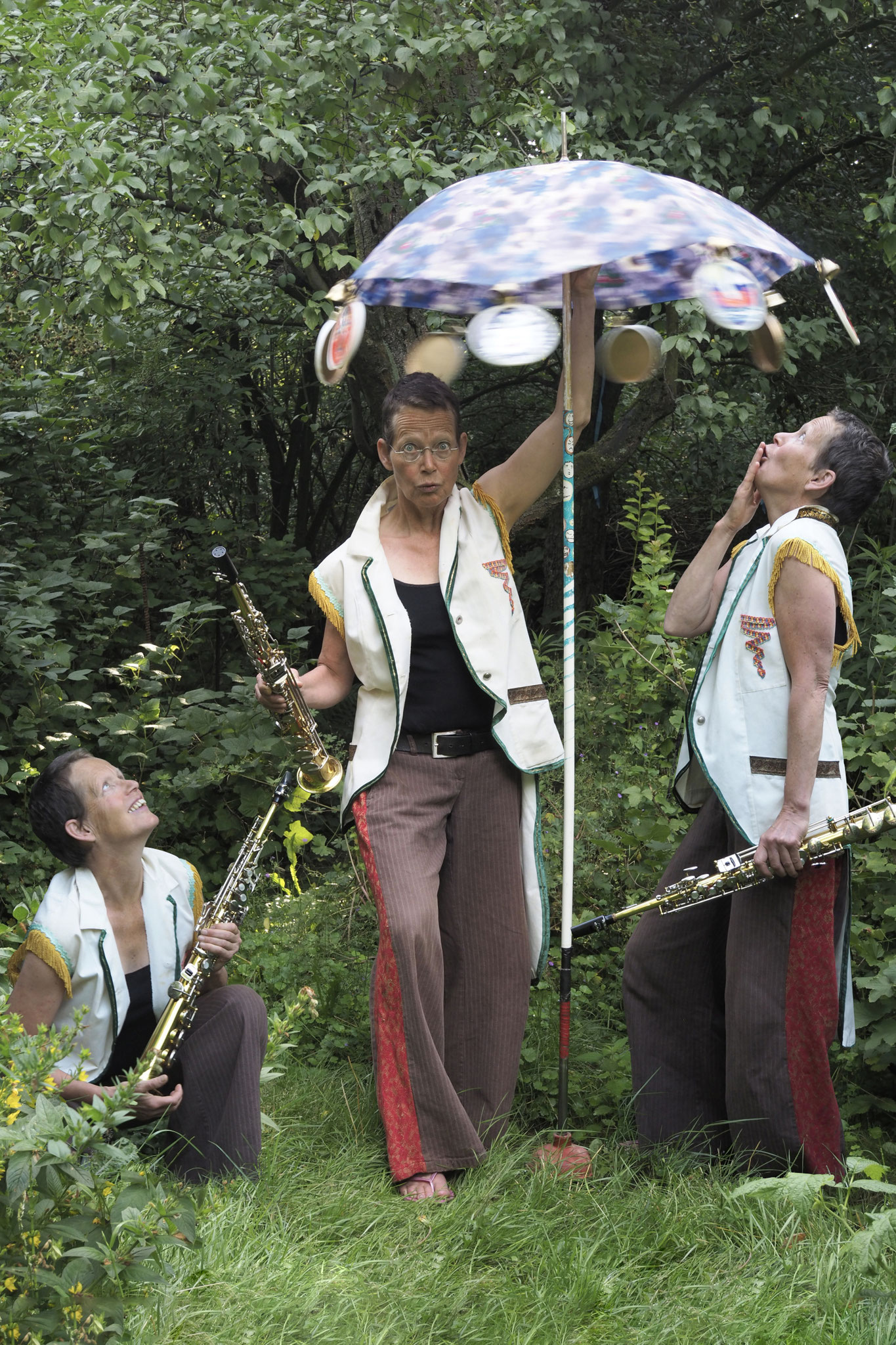Porträt der Musikerin Anne Wiemann. Sie steht in einem Garten unter einem Sonnenschirm. Sie ist dreimal im gleichen Bild und hat immer ein Sopransaxophon in der Hand. Sie hockt im Gras, steht unter dem Schirm, und schaut von der Seite erstaunt zu.