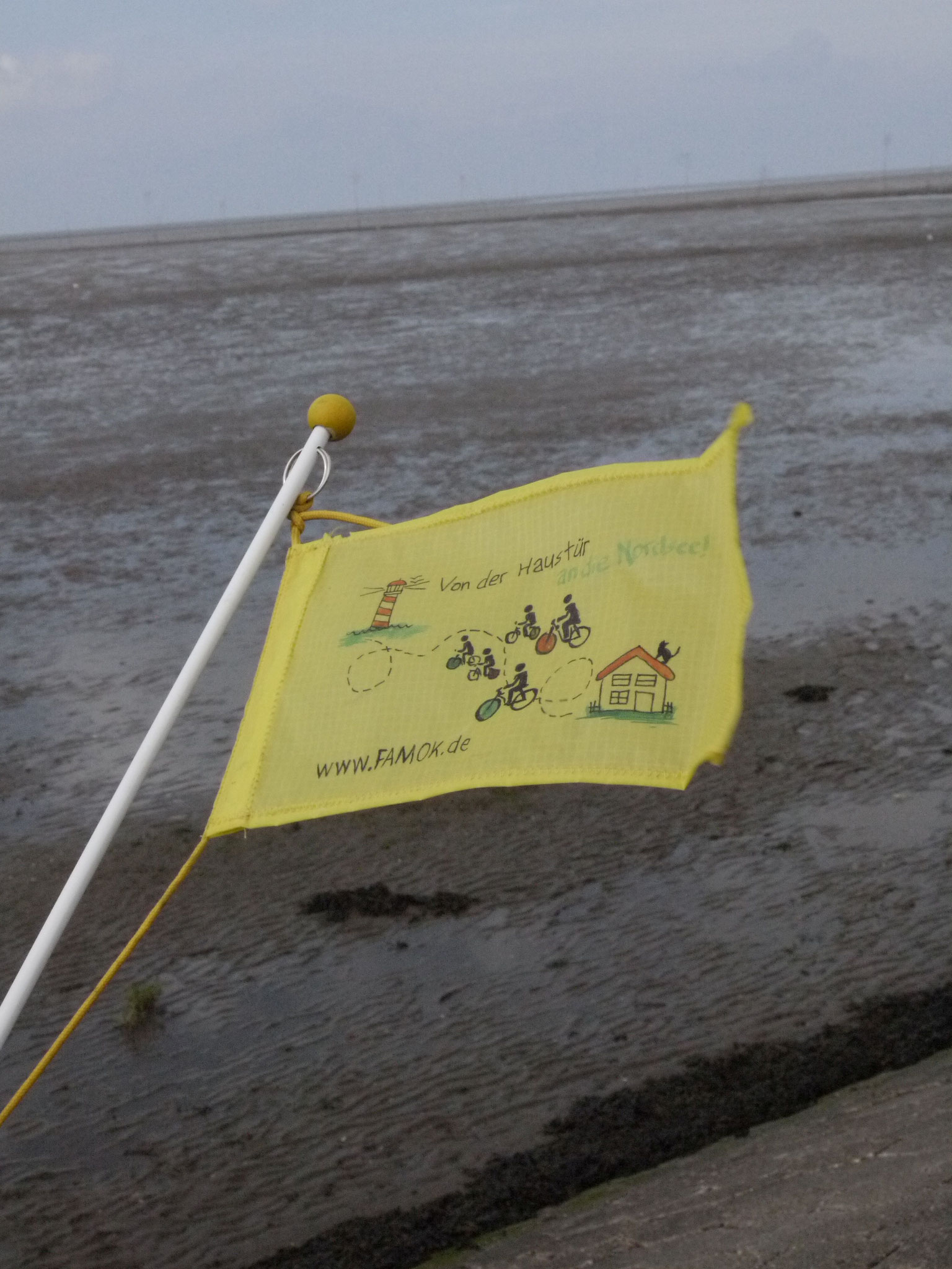 Unsere Tourflagge, im Hintergrund das verebbte Meer