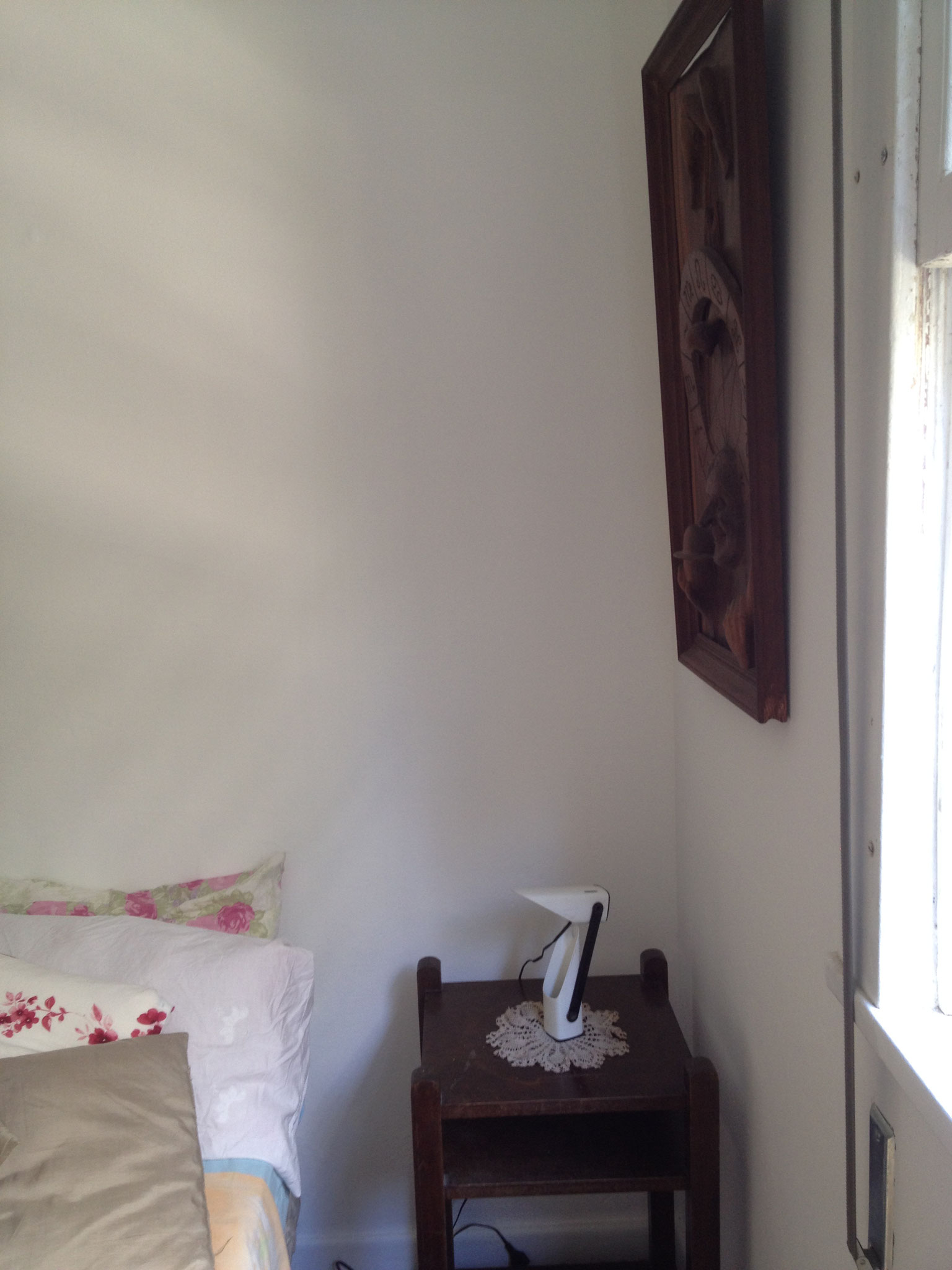 bedside table and wood skulpture on the wall of the second sleeping room