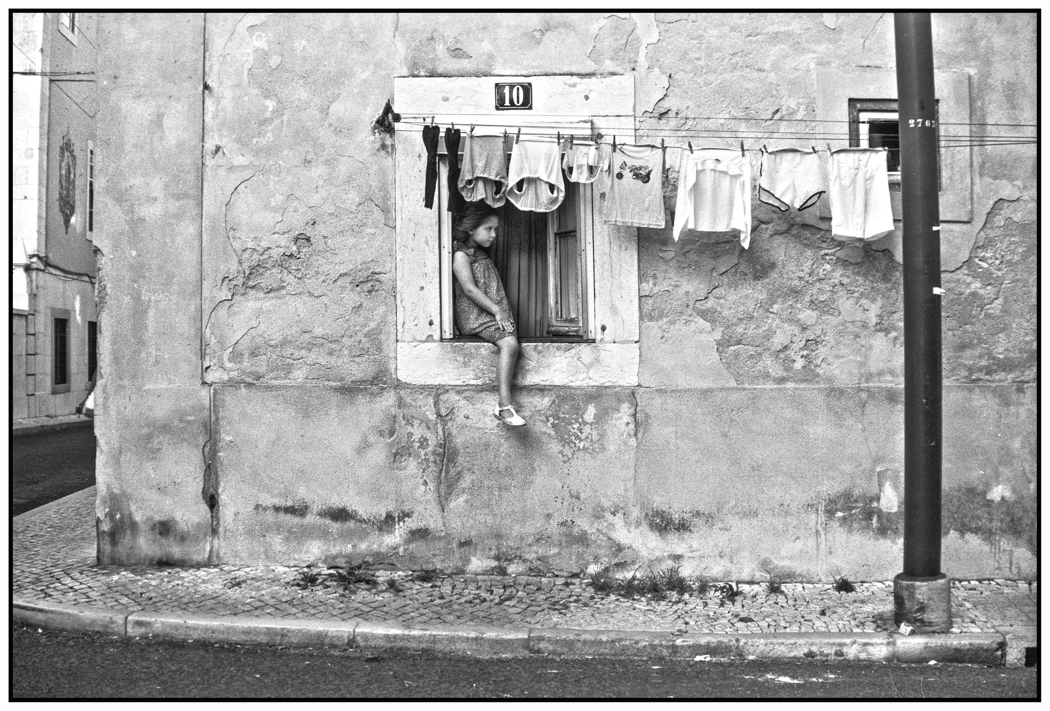 Girl sitting in window frame, Portugal