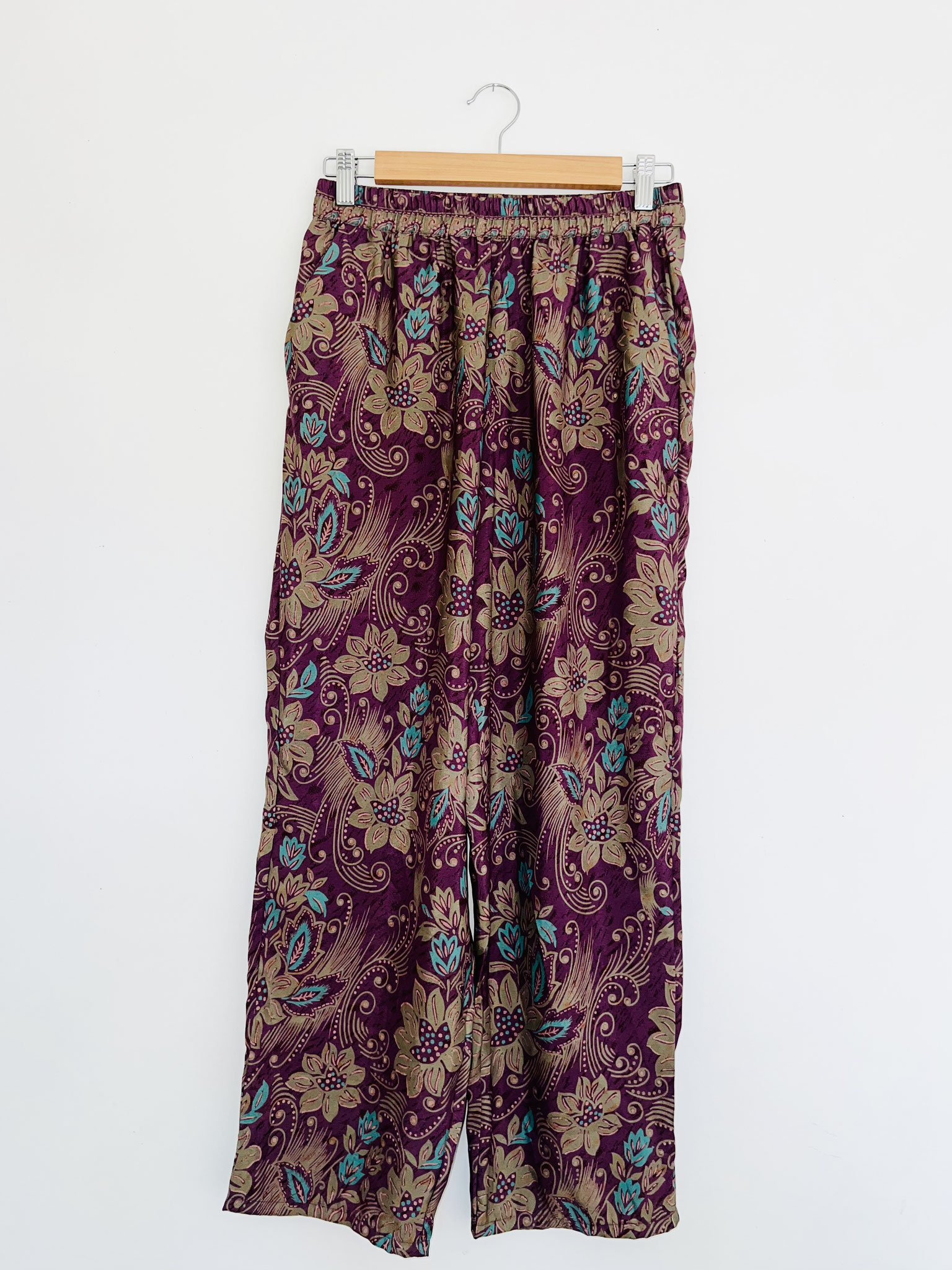 Pantalon violet en sari recyclé avec motifs indiens floraux et grosses fleurs vert turquoise suspendu sur cintre, vue complète