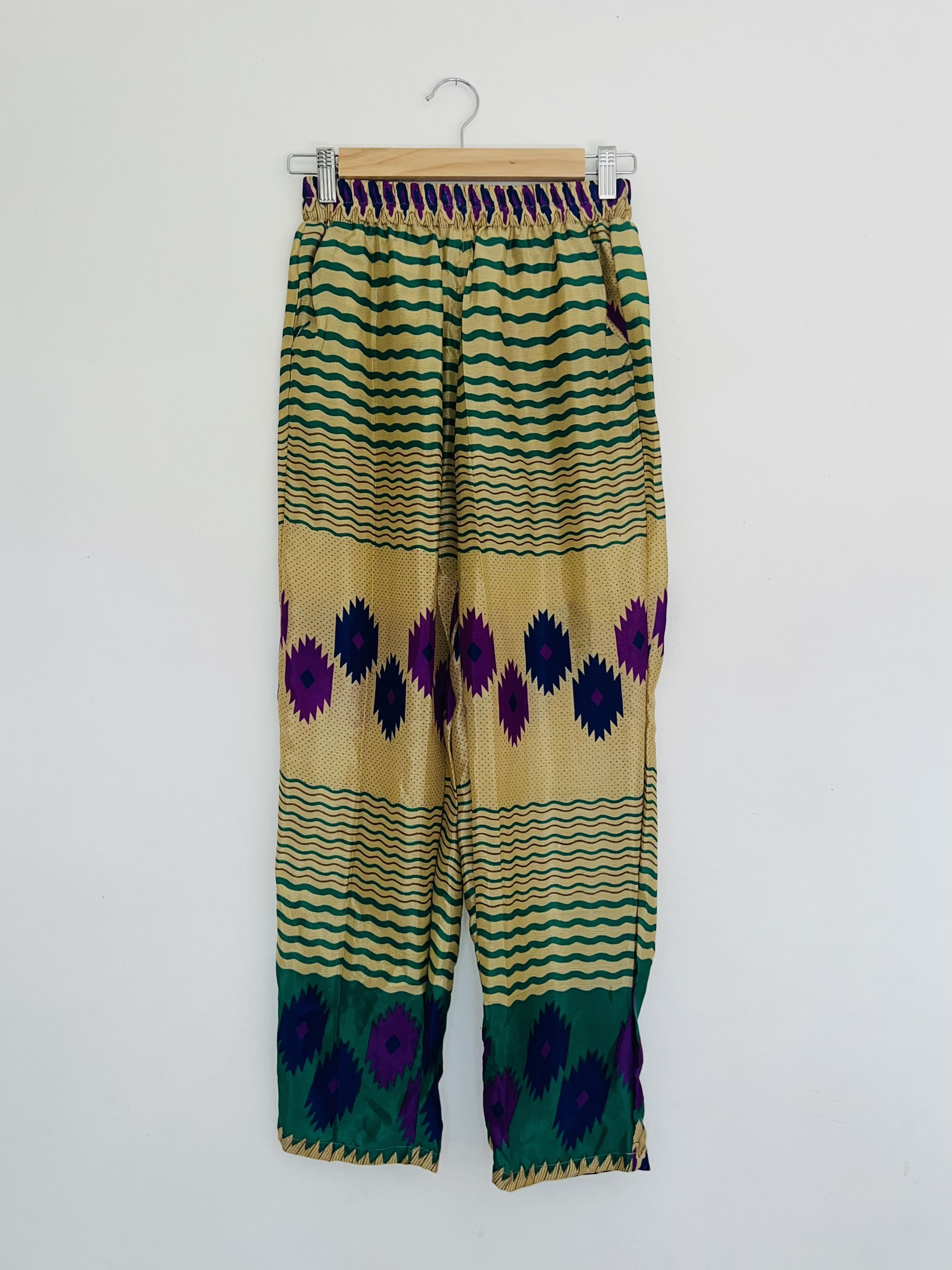 Détail du haut – Liserés vert sapin et motifs géométriques violets sur fond jaune pâle