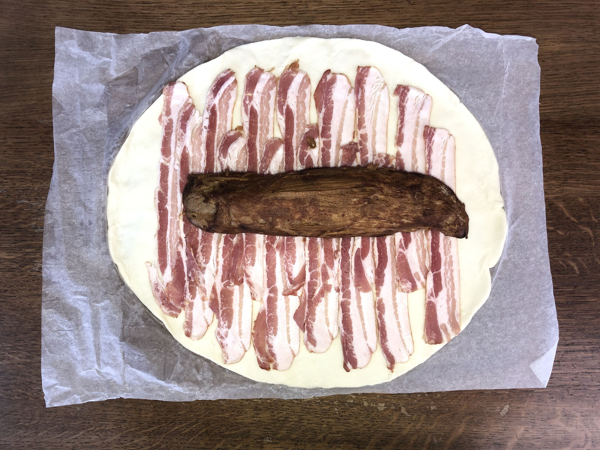 Filet anbraten, marinieren und auf mit Speck belegten Teig legen.