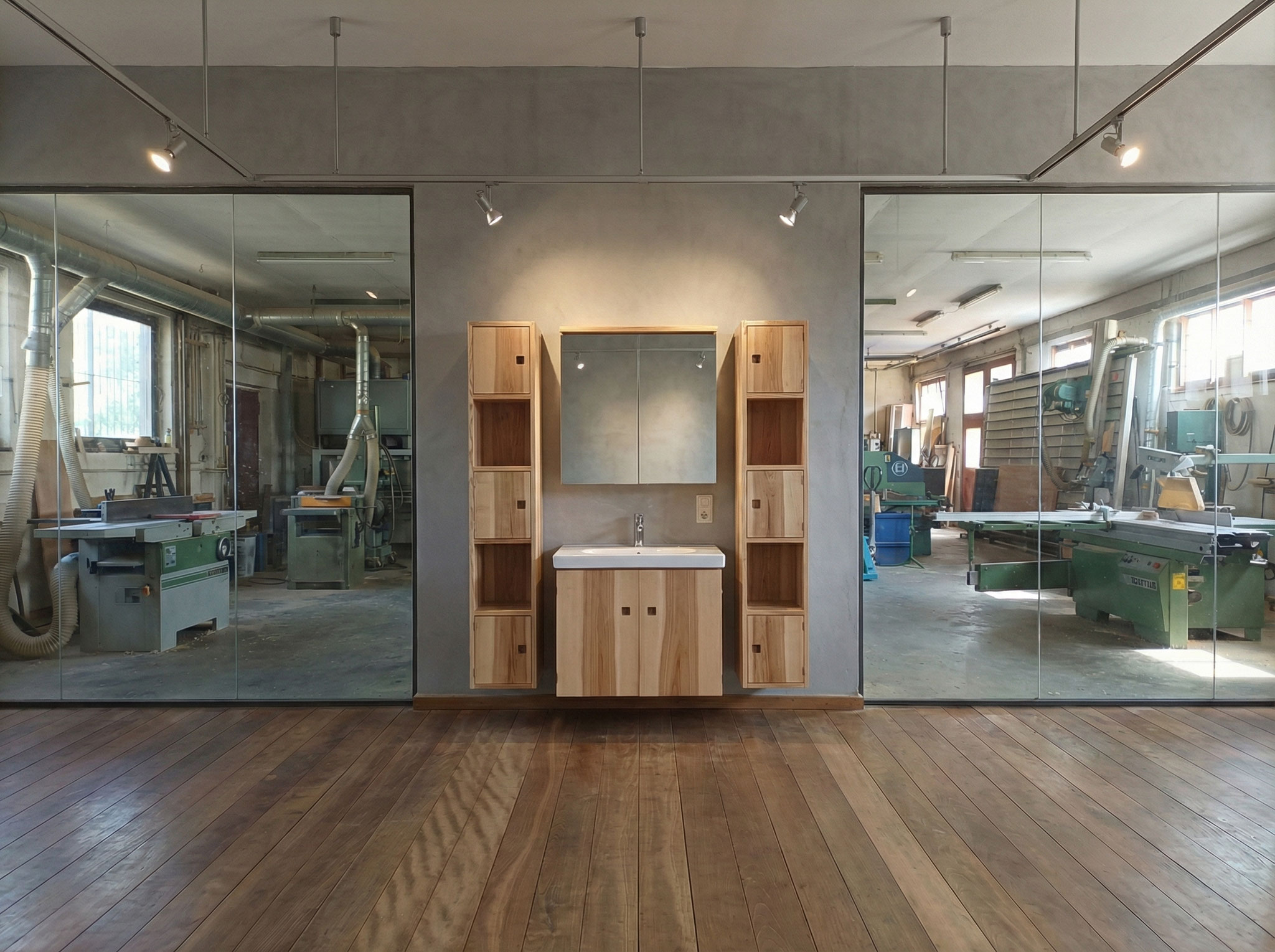 Eine Installation von Badmöbeln in Eschenholz mit Waschtischkästchen und 2 säulenartigen Regalkombinationen und Spiegelschrank im Showroom der Schreinerei Kramhöller mit Blick in die Werkstatt.