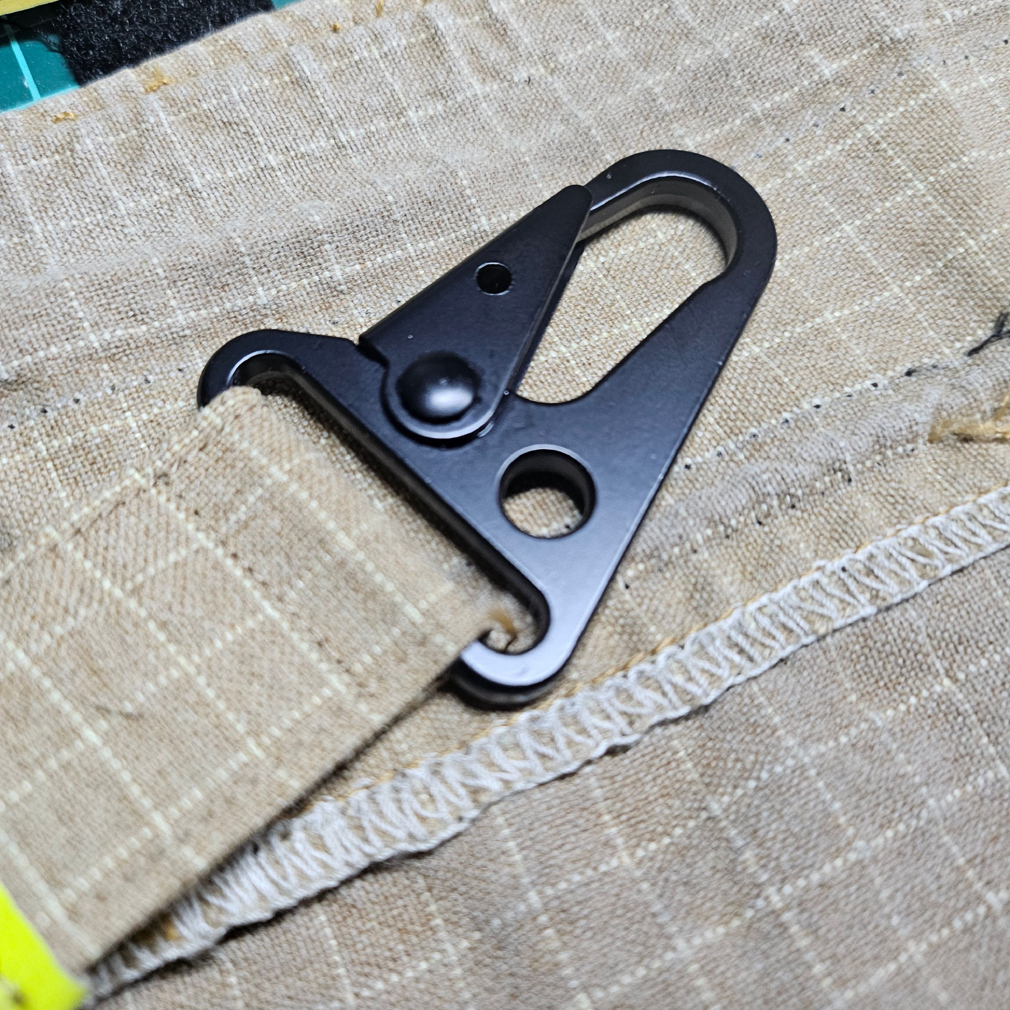 Taktischer Karabinerhaken an strapazierfähigem Heldenstoff. Detailansicht der stabilen Naht und des Karabiners für Feuerwehr-Ausrüstung.