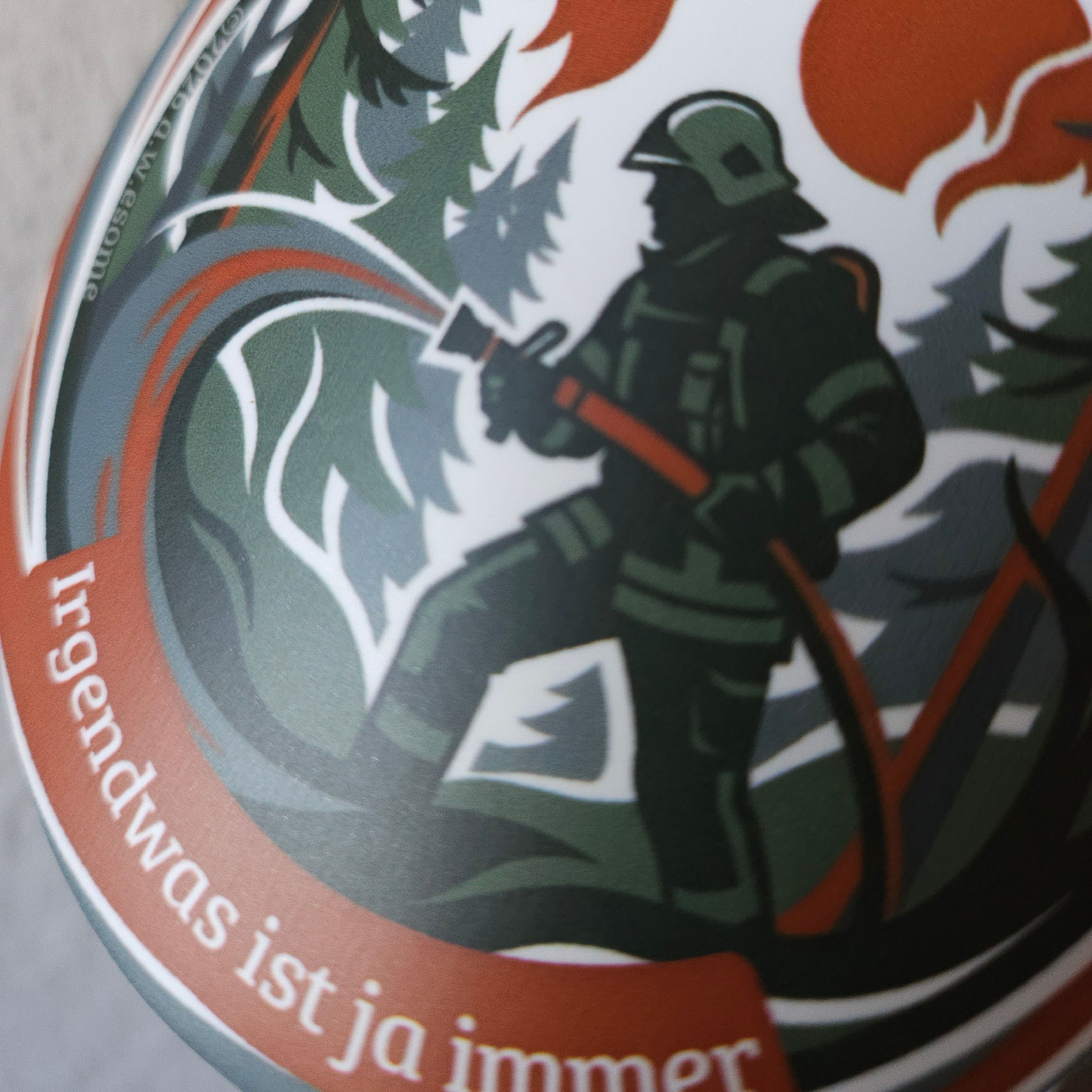Runder Feuerwehr-Sticker der Einsatzserie zeigt eine Einsatzkraft mit Löschschlauch bei einem Waldbrand im Forst.
