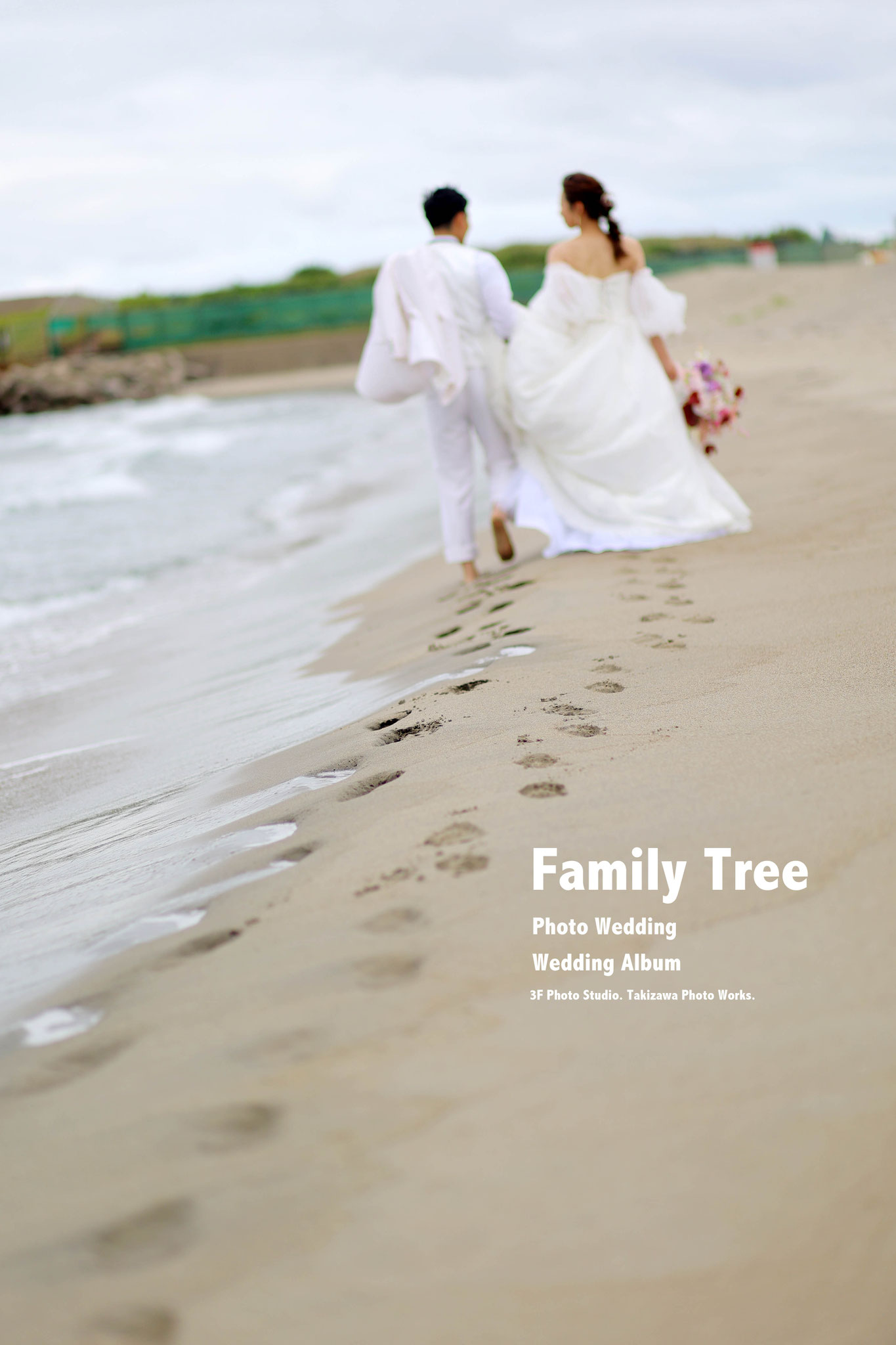 新郎新婦が浜辺を歩きその足跡にピントを合わせ新郎新婦はボカすドラマチックな写真