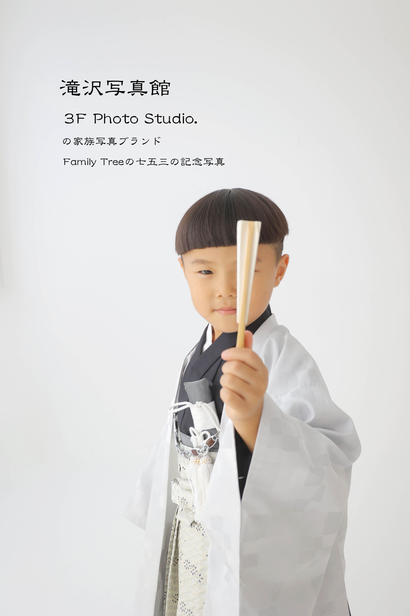 センスを顔の前に片目を隠してポーズを決める男の子の七五三写真