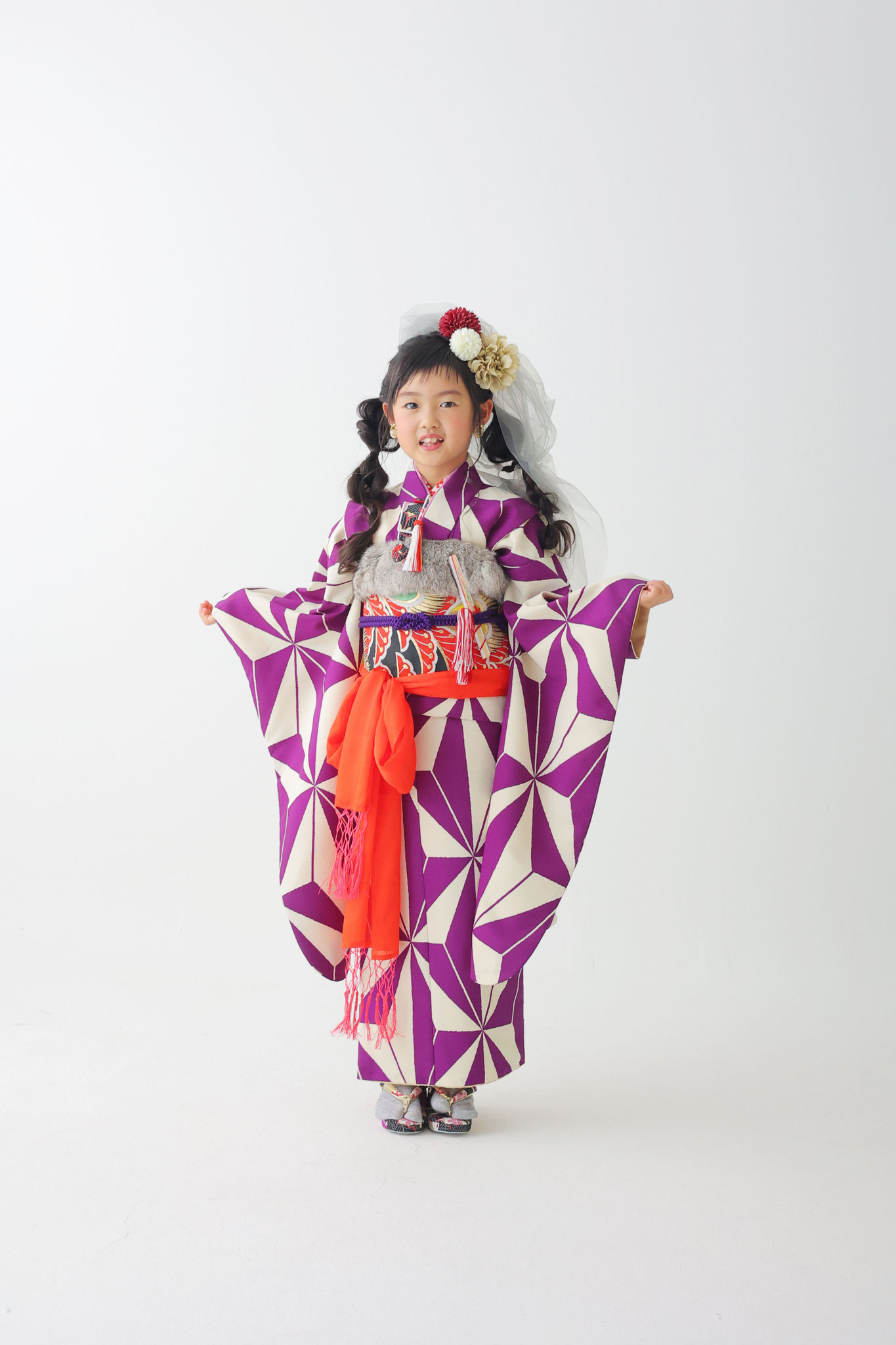 両袂を開いてカメラ目線でにっこり微笑む紫の着物の女の子
