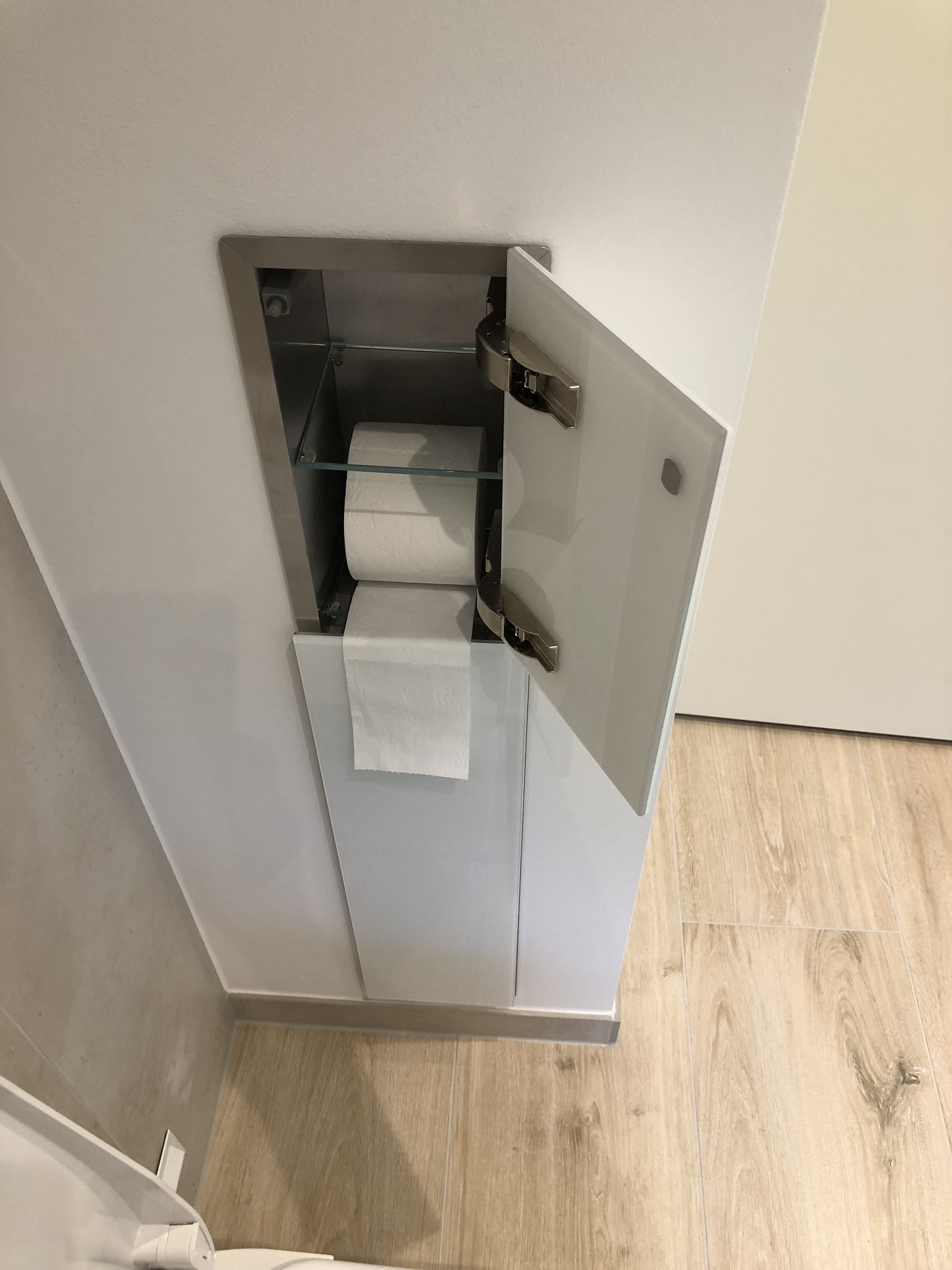 (links) Unterputzelement für WC-Garnitur (Toilettenpapier, Bürste etc.) aus Edelstahl, mit Weissglas-Front und "push to open"-Schließfunktion