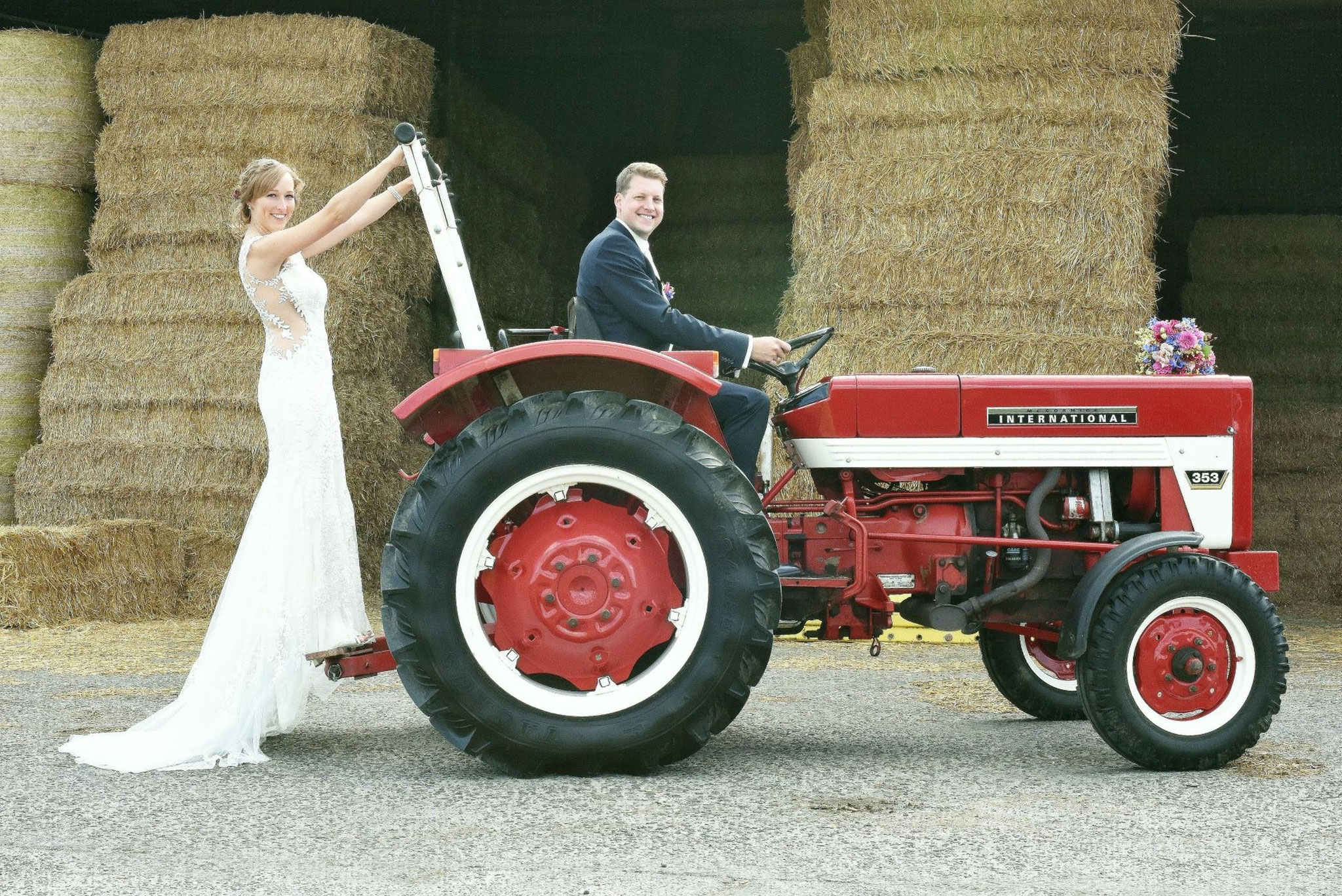 Brautpaar mit rotem Traktor – rustikale Hochzeit auf dem Land