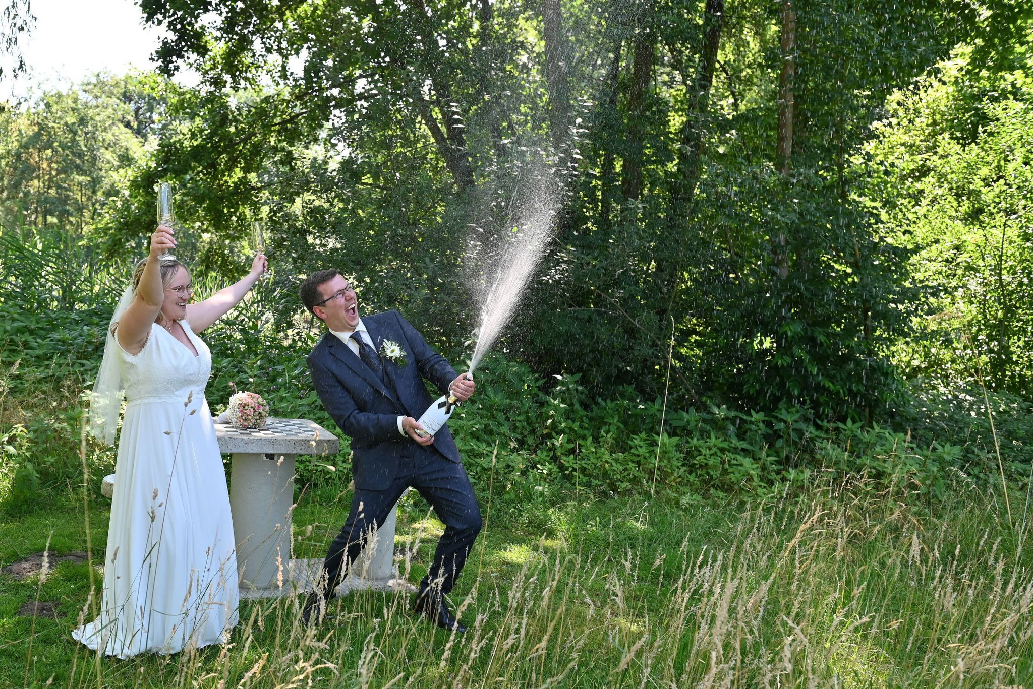 Brautpaar spritzt Champagner im Grünen – lebendige Hochzeitsreportage