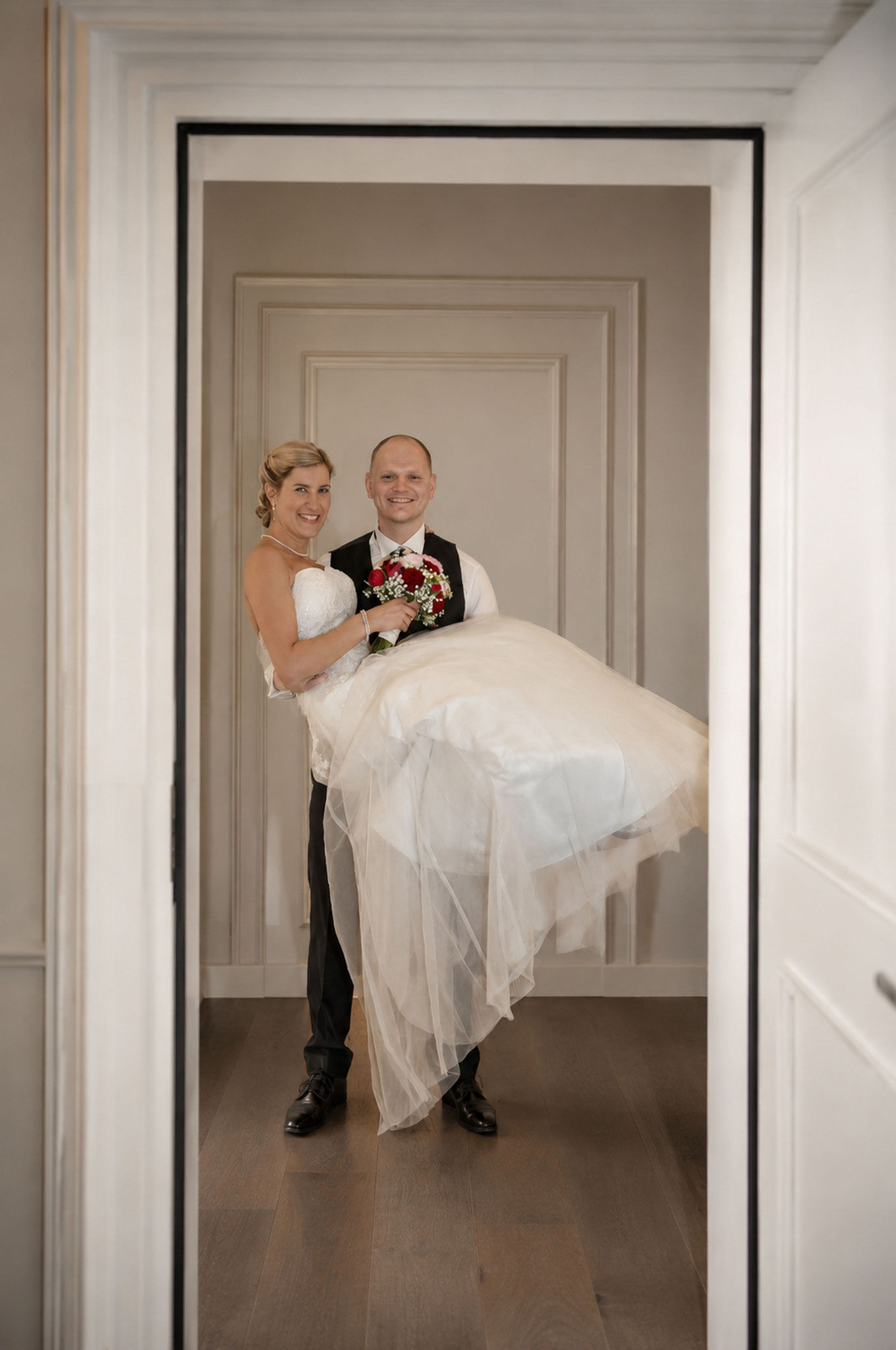 Bräutigam hebt Braut über die Schwelle zur Hochzeitsnacht