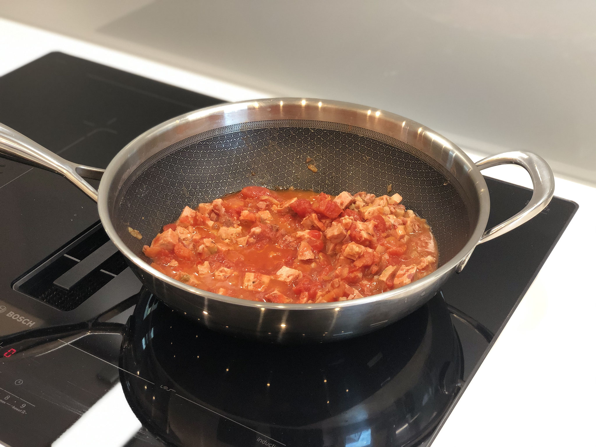 Nun die Zwiebel in Würfel schneiden und mit etwas Olivenöl in der Pfanne glasig andünsten. Knoblauch hinzupressen und mit der Tomatensauce und Tomatenmark aufgießen und einköcheln lassen..