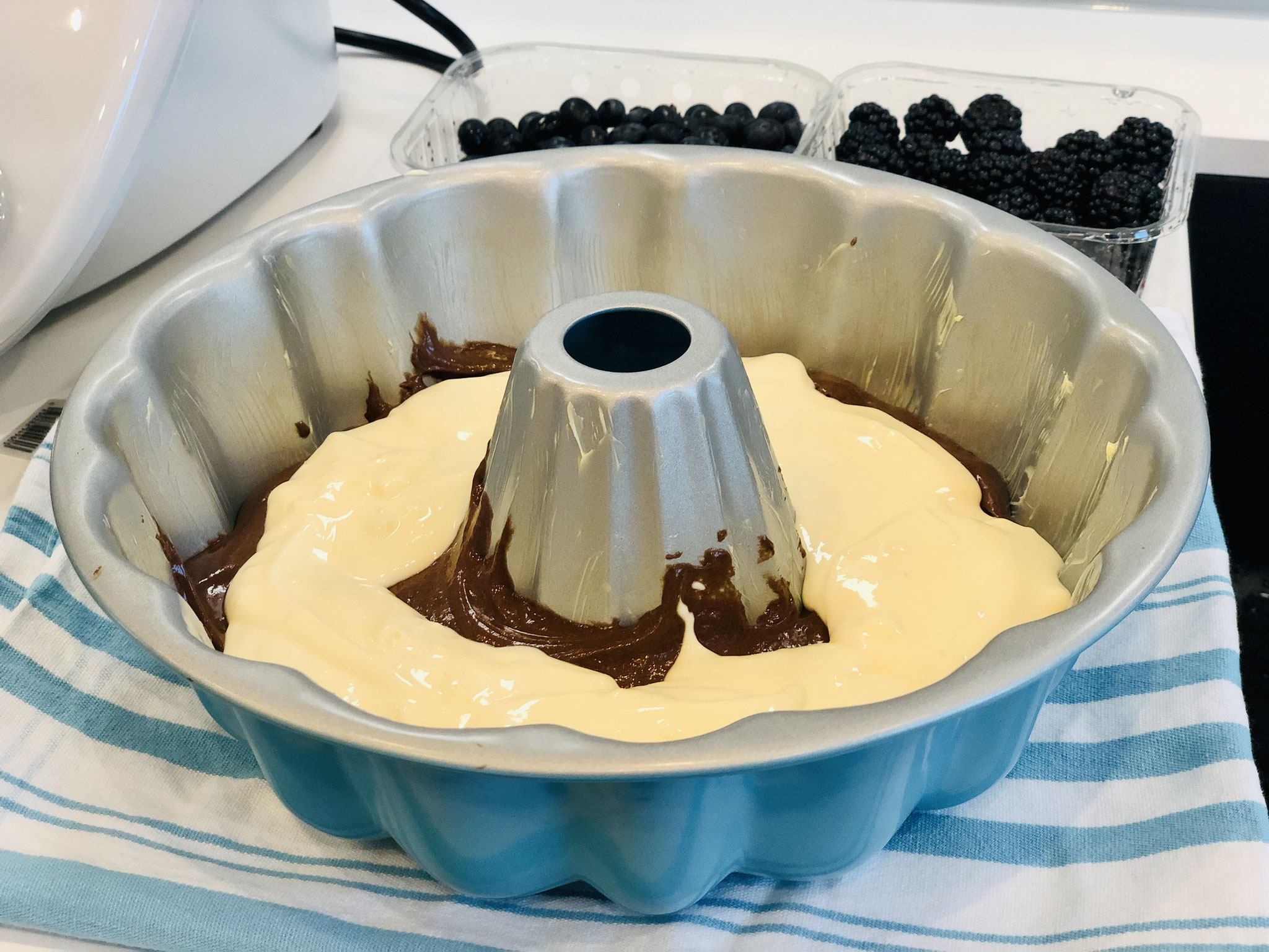 Zuerst kommt ein Teil des dunklen Schokoladenteig in die Kranzform von Pampered Chef und darauf die Quarkmasse mit einem Teil der Früchte..