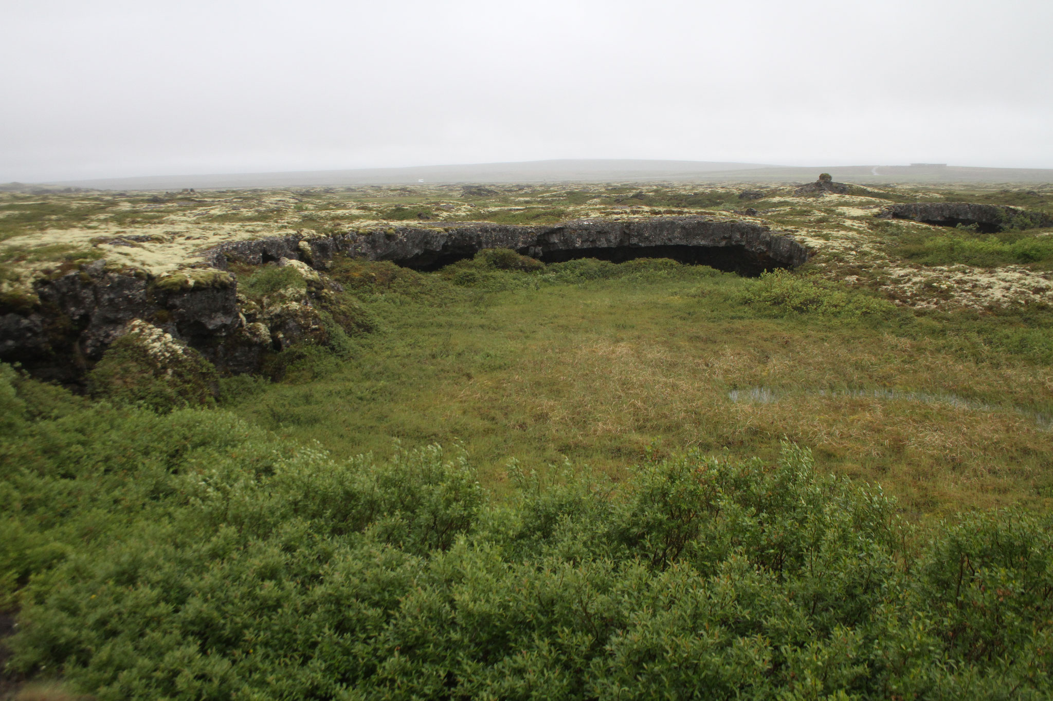 Der See ist umgeben von einer tundrartigen Landschaft mit vielen Lavahöhlen