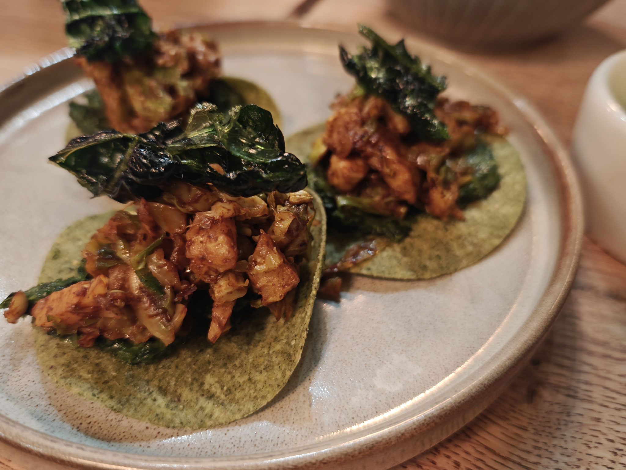 Taco aus Grünkohl und Mais, Kohlsprossen mit Mole (Chili Schokoladensauce aus Mexiko) frittierter Schwarzkohl und Tamarillo Marinade.