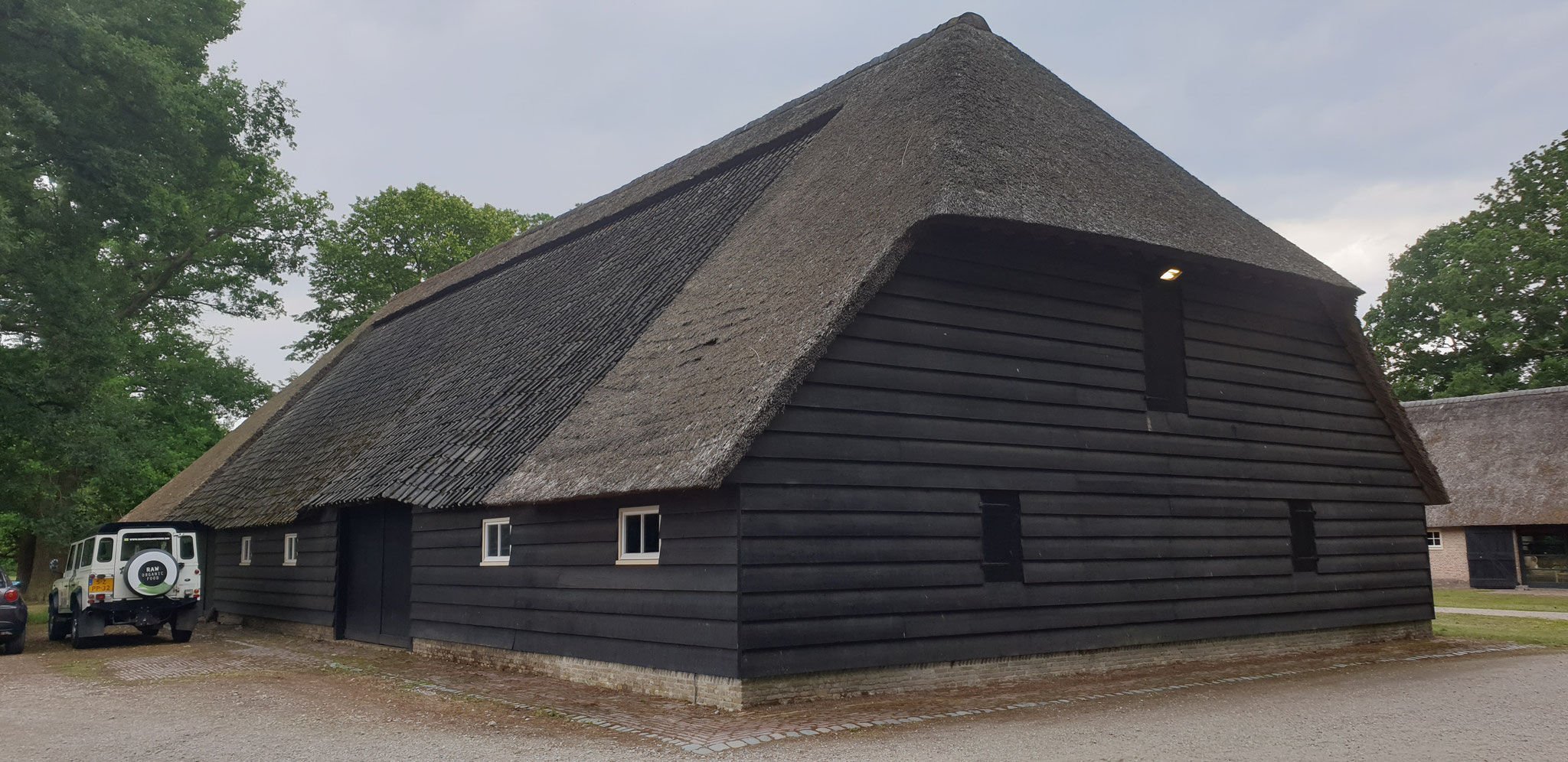 De schuur: noordelijke kopgevel en oostelijke langsgevel. De dakwelvingen boven de banpoorten van de dwarsdelen zijn hier lager. 