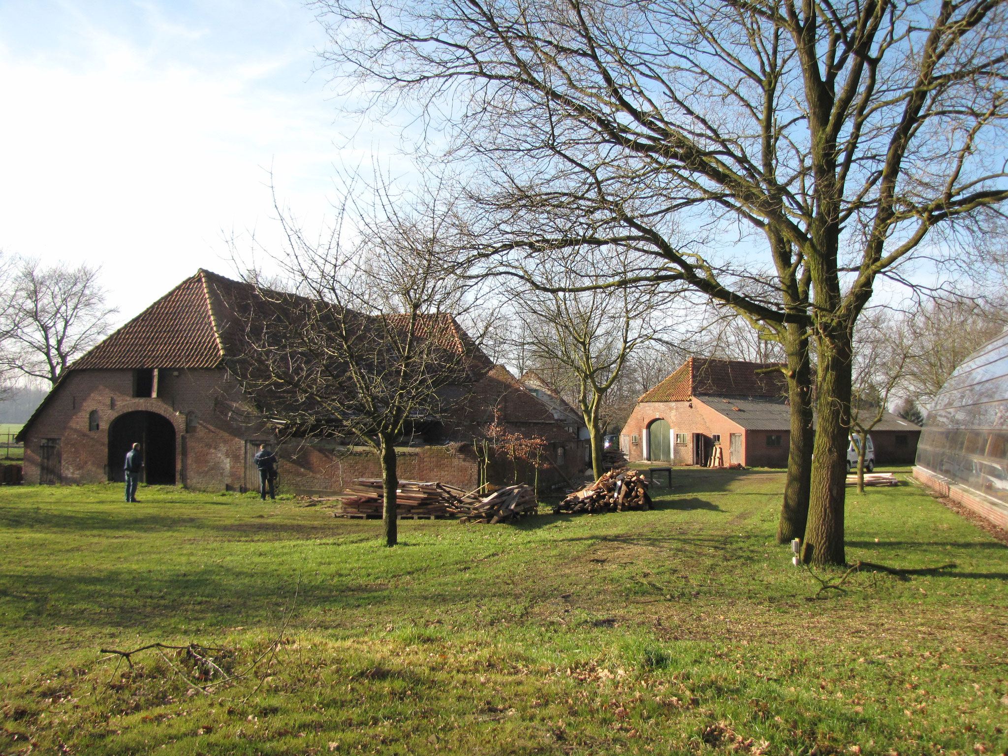 De verschillende volumes, gezien vanuit het noorden: links de T-boerderij, rechtsachter de schuur, rechts voor de glazen kas. 