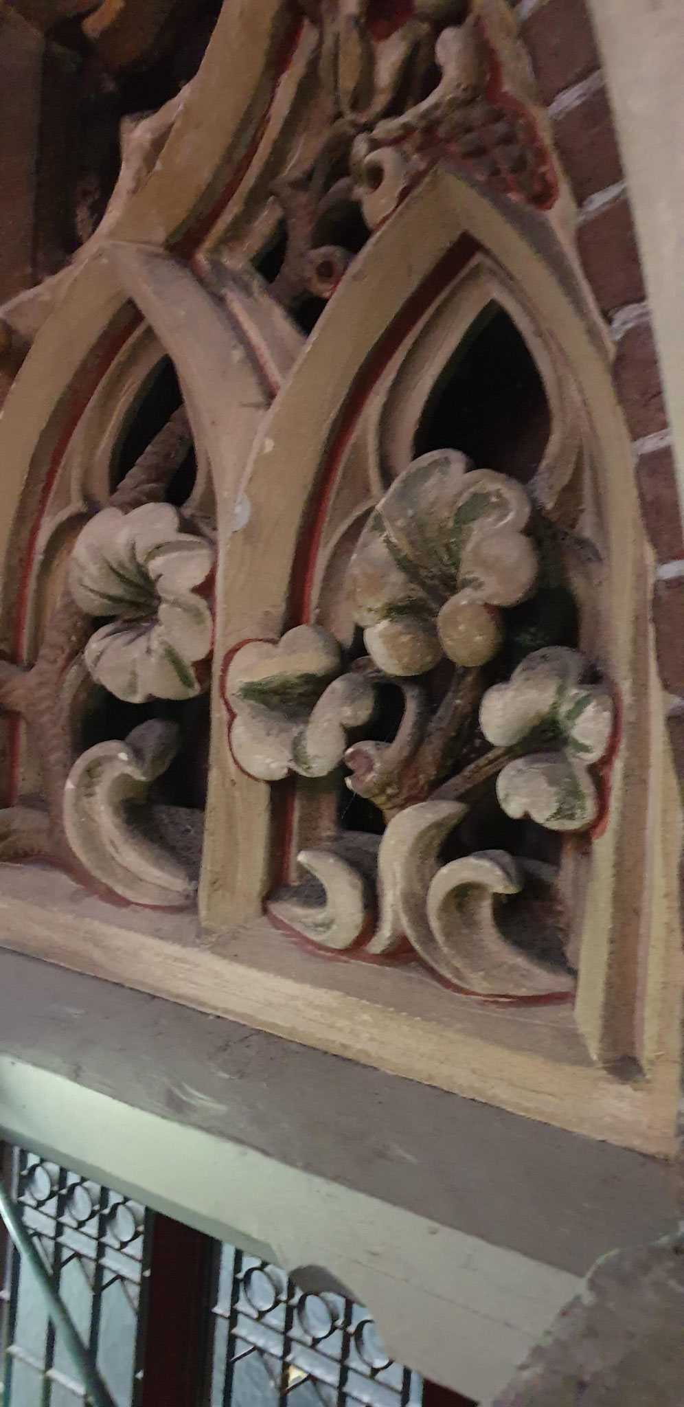 Ajourwerk met oorspronkelijke polychromie in het boogveld boven een van de portalen in het noordelijke transept.
