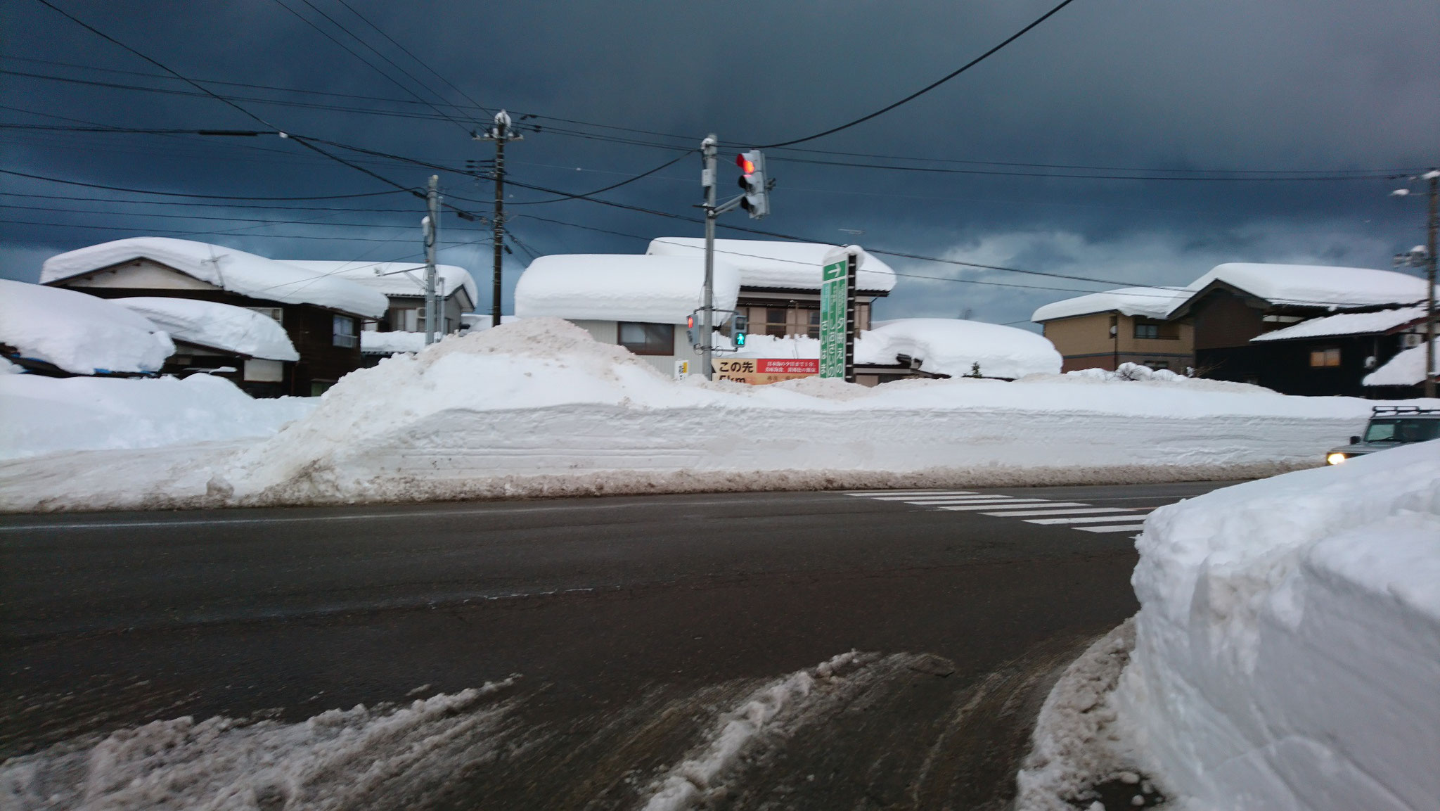 踏切のそばにある国道8号線の交差点。歩道の除雪はなく、国道を歩く必要があります。