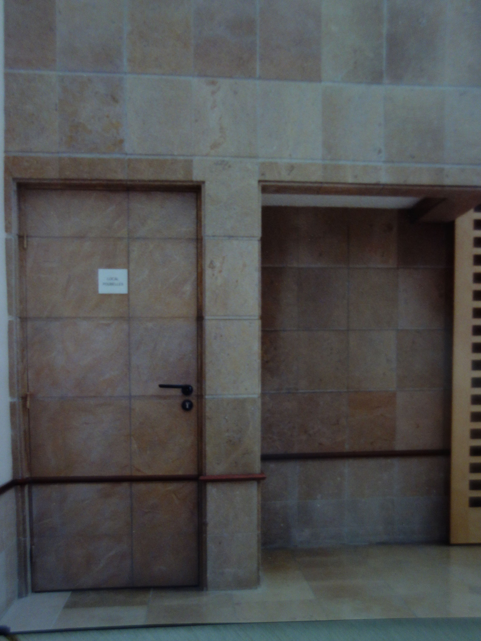 Hall de bureaux: peinture de la porte en fausses pierres pour la faire disparaître 