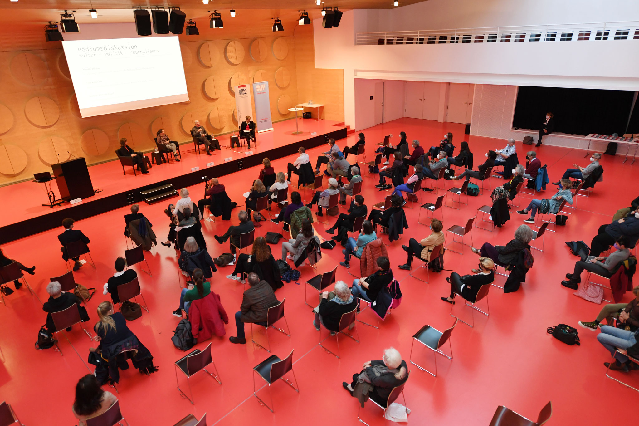 Blick von der Empore auf Publikum und Diskussionsrunde. Auf dem Podium, von links nach rechts: Sibylle Thelen, Kathrin Horster-Rapp, Tim Schleider, Anja Dargatz.