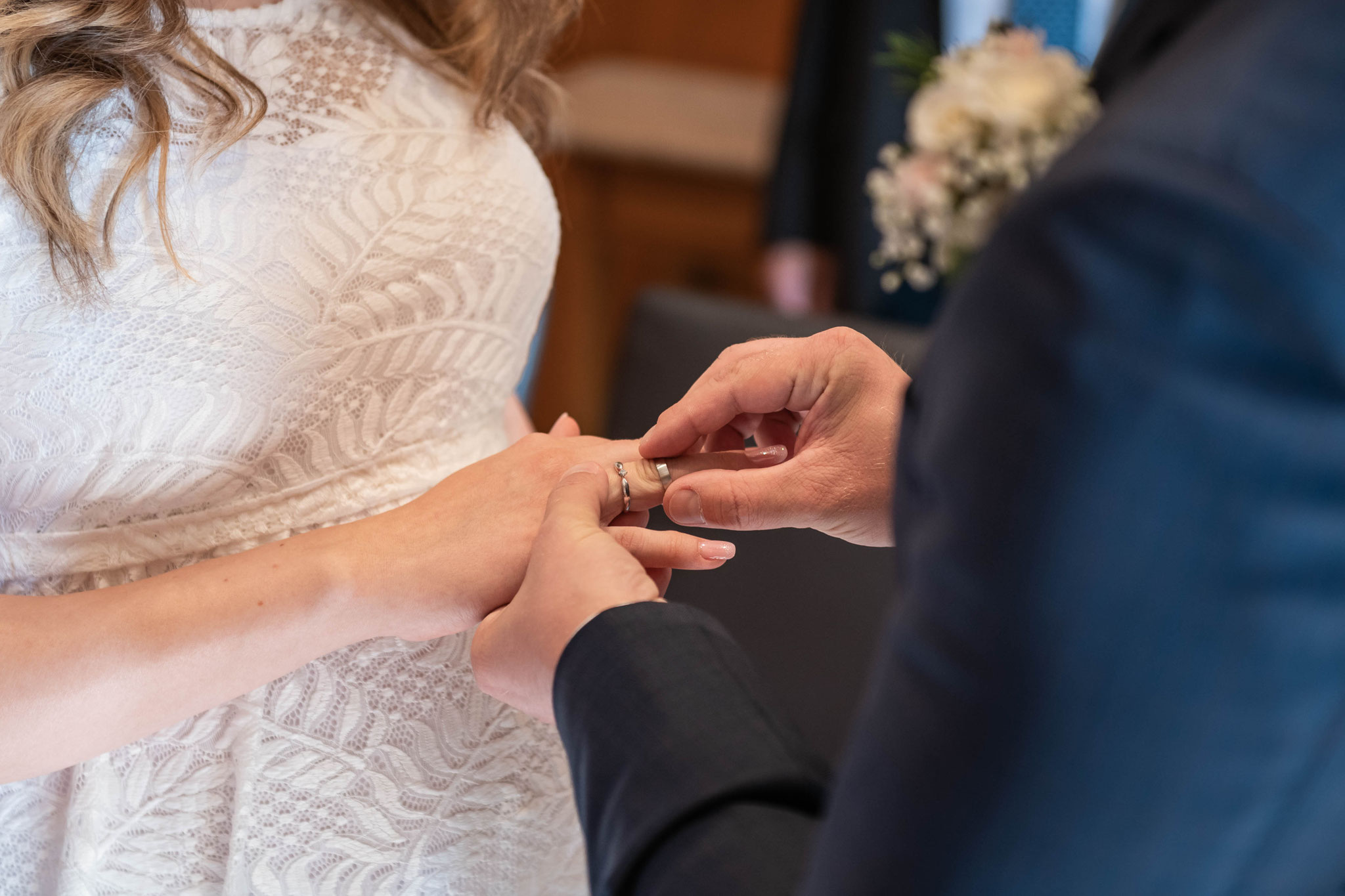 Bräutigam steckt seiner Braut den Heiratsring an den Finger