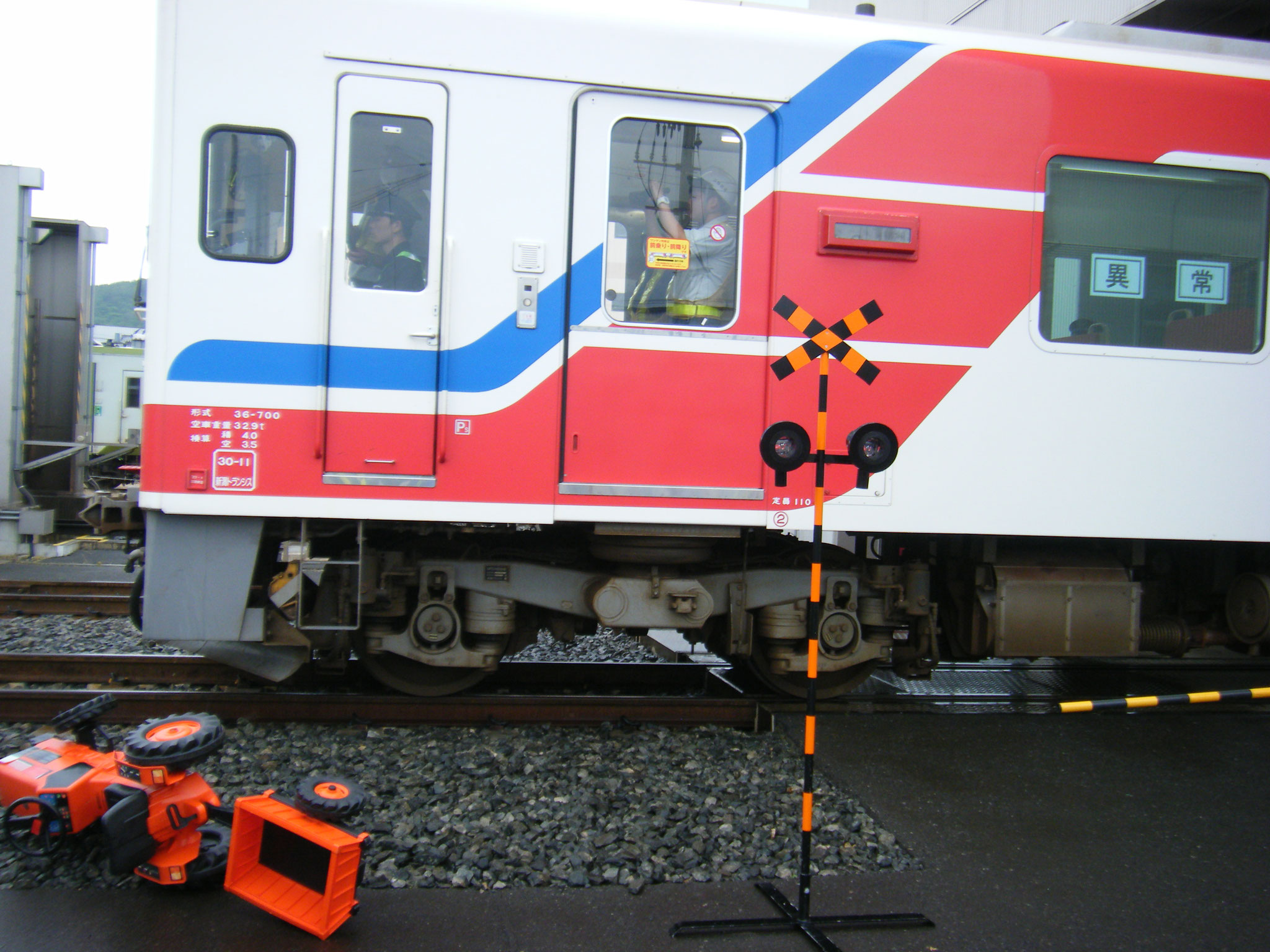 踏切（事故現場）を走行する列車　左下は大破したトラクター