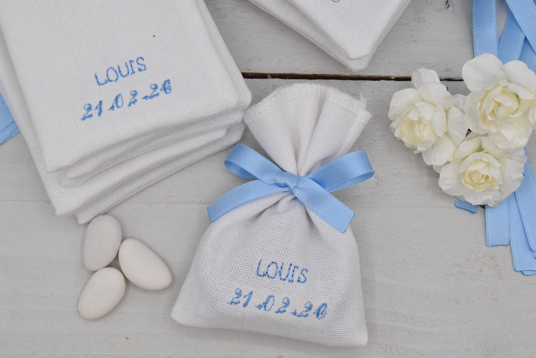 Sachet dragées réalisé en coton blanc et personnalisé par la broderie au fil bleu ciel. Belles finitions, le ruban bleu ciel satin (qualité made in France) est cousu directement sur le sachet.