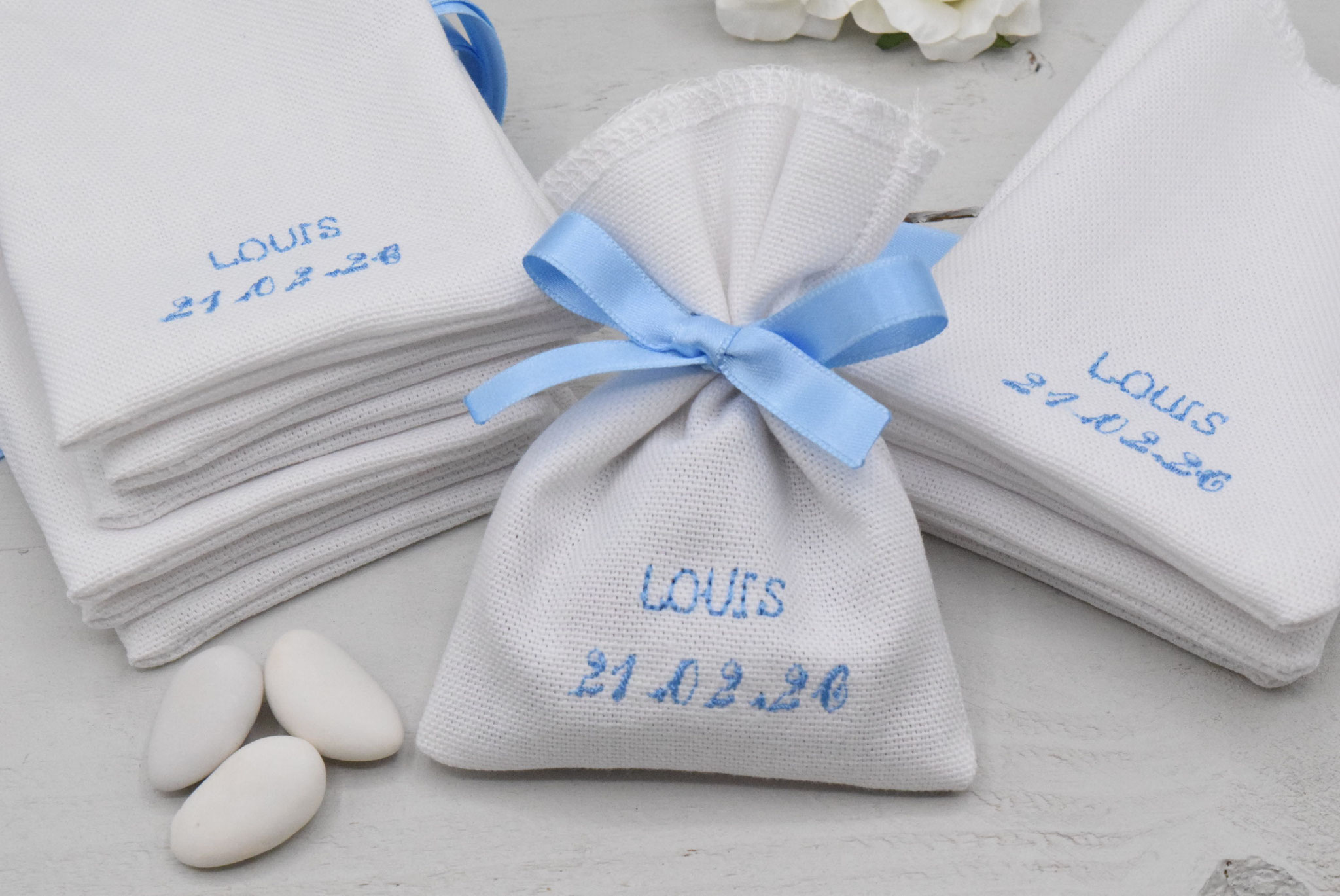 Sachet dragées réalisé en coton blanc et personnalisé par la broderie au fil bleu ciel. Belles finitions, le ruban bleu ciel satin (qualité made in France) est cousu directement sur le sachet.