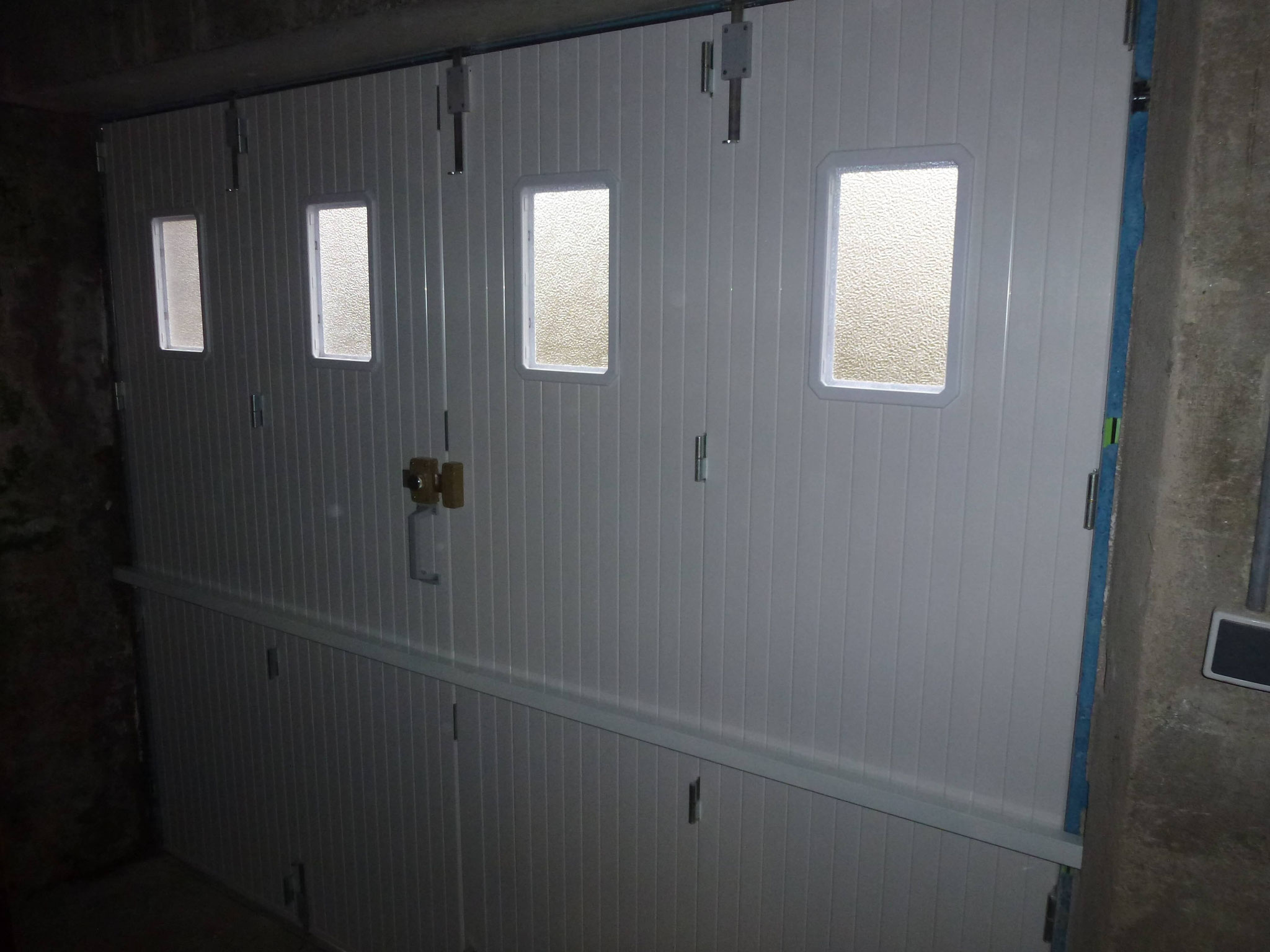 Porte de garage PVC avec hublot et barre de renfort vue de l'intérieure gauche.