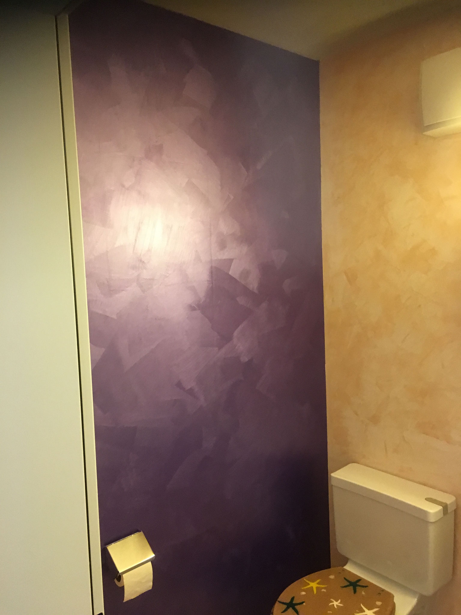 Die anliegende Wand ist mit dem System "Sabulador-Soft", im Farbton "Violett" gestaltet. Die leicht sandige Oberfläche und der Glanz gibt der Wand einen speziellen Touch.