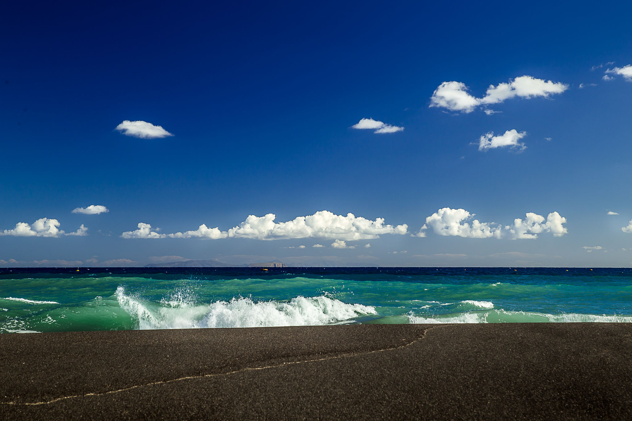 black beach, turquoise water, blue sky