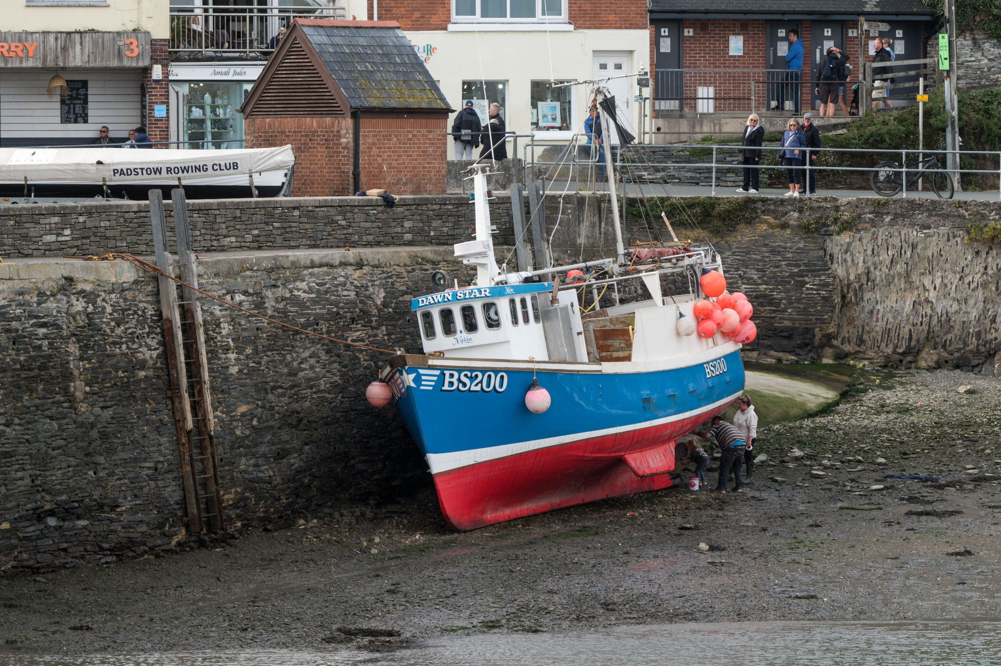 ein Schiff lehnt sich an die Hafenmauer von Padstow
