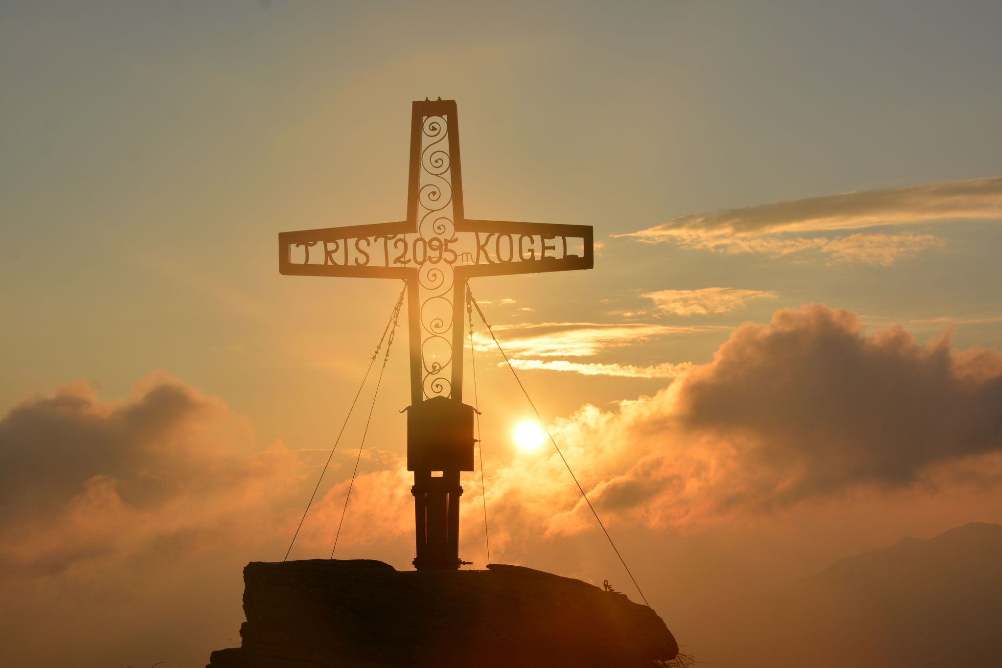 Nach einer Tour durch die noch schwarze Bergnacht wartet auf dem Gipfel bei Sonnenaufgang ein spektakuläres Bergpanorama der Kitzbüheler Alpen in leuchtendem Orange. ©www.unterschwarzach.at