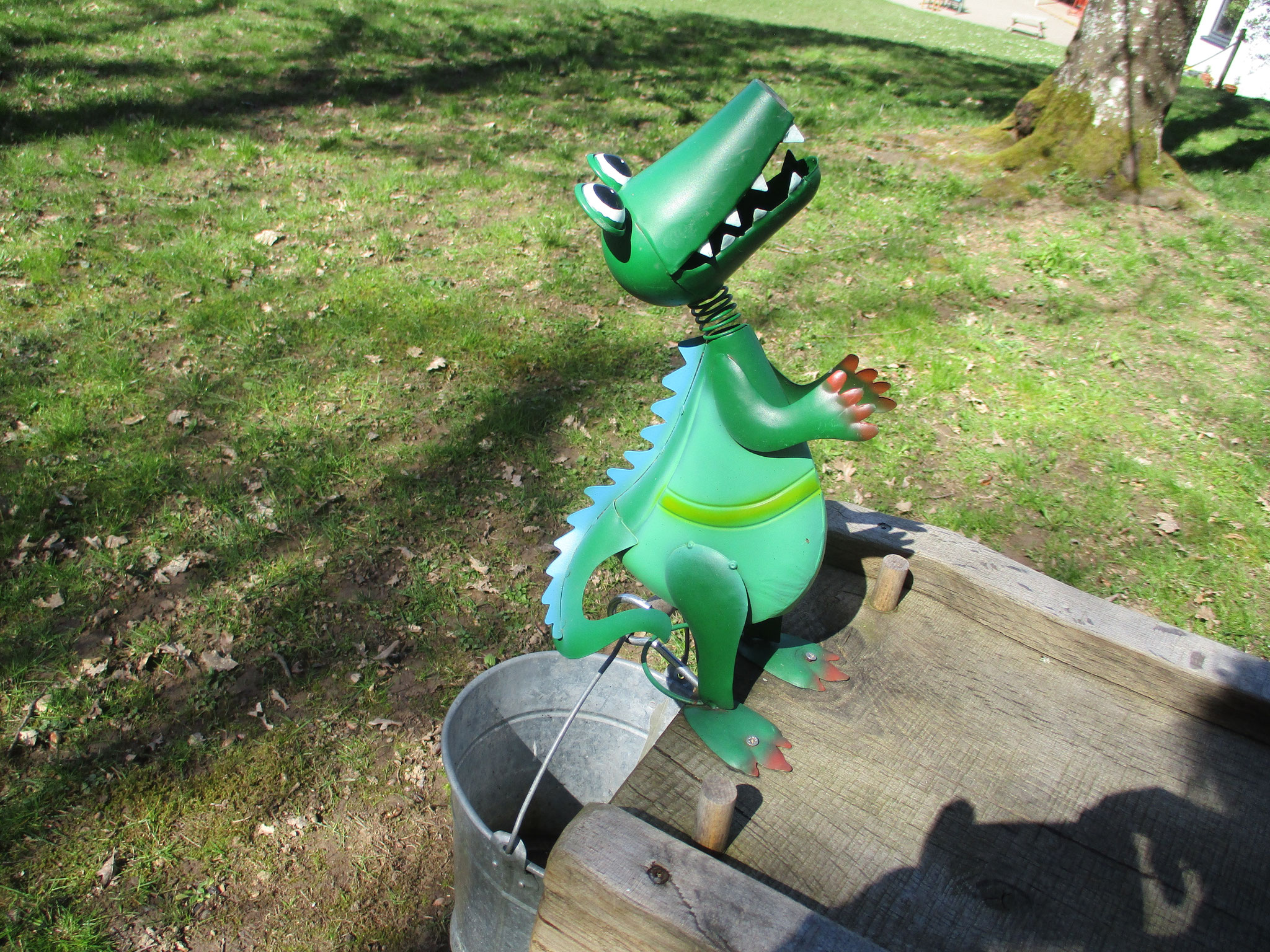 Drache freut sich, wenn eine Kugel in den Eimer fällt.