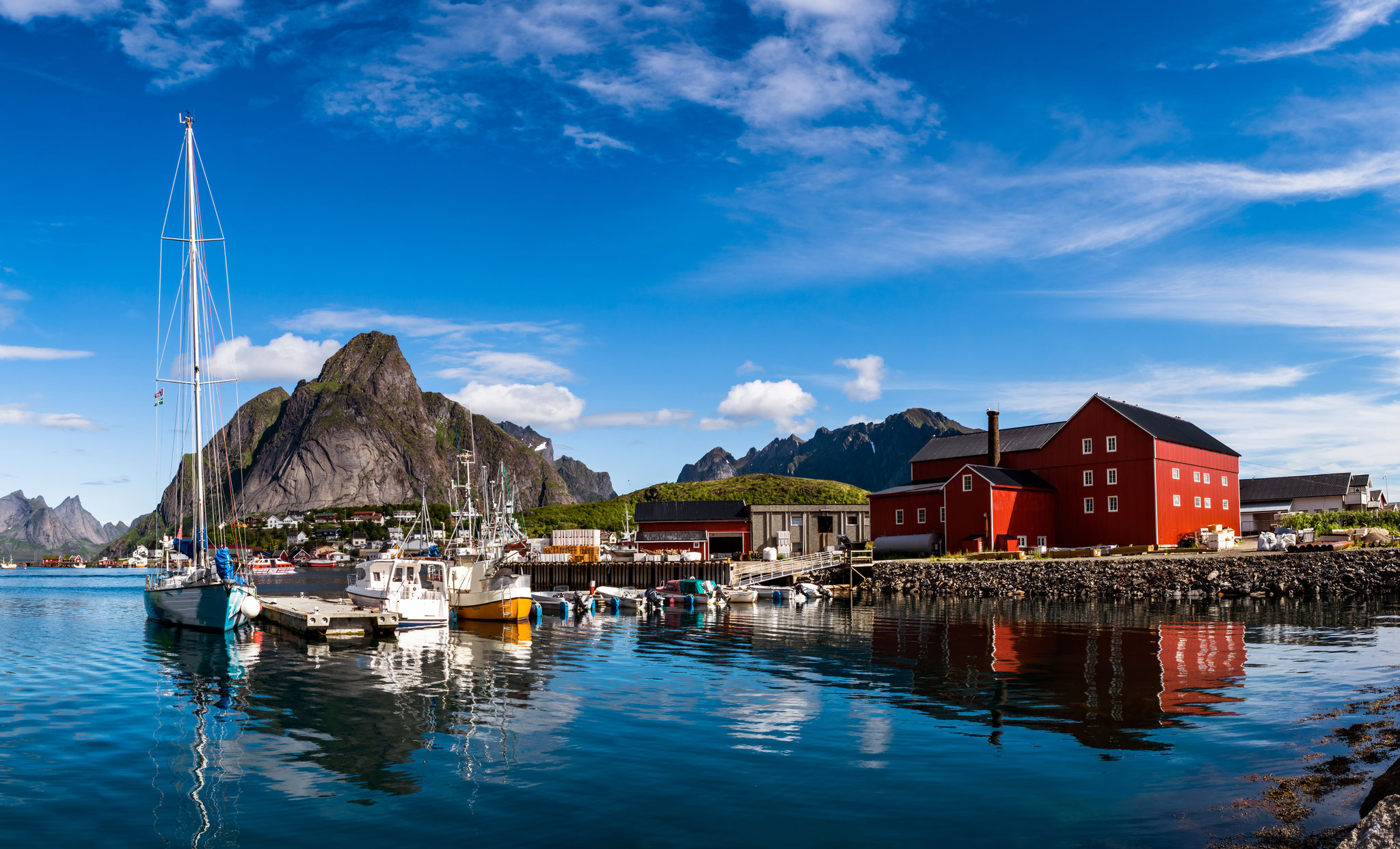 Bikepacking Norwegen - Bikepacking Lofoten Hafen mit roten Fischerhäusern und Bergen im Hintergrund – Küstenroute Norwegen