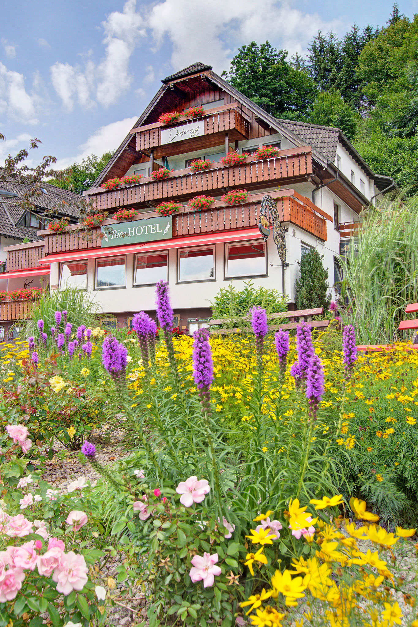 hotelfoto hotel von aussen und im vordergrund viele blumen