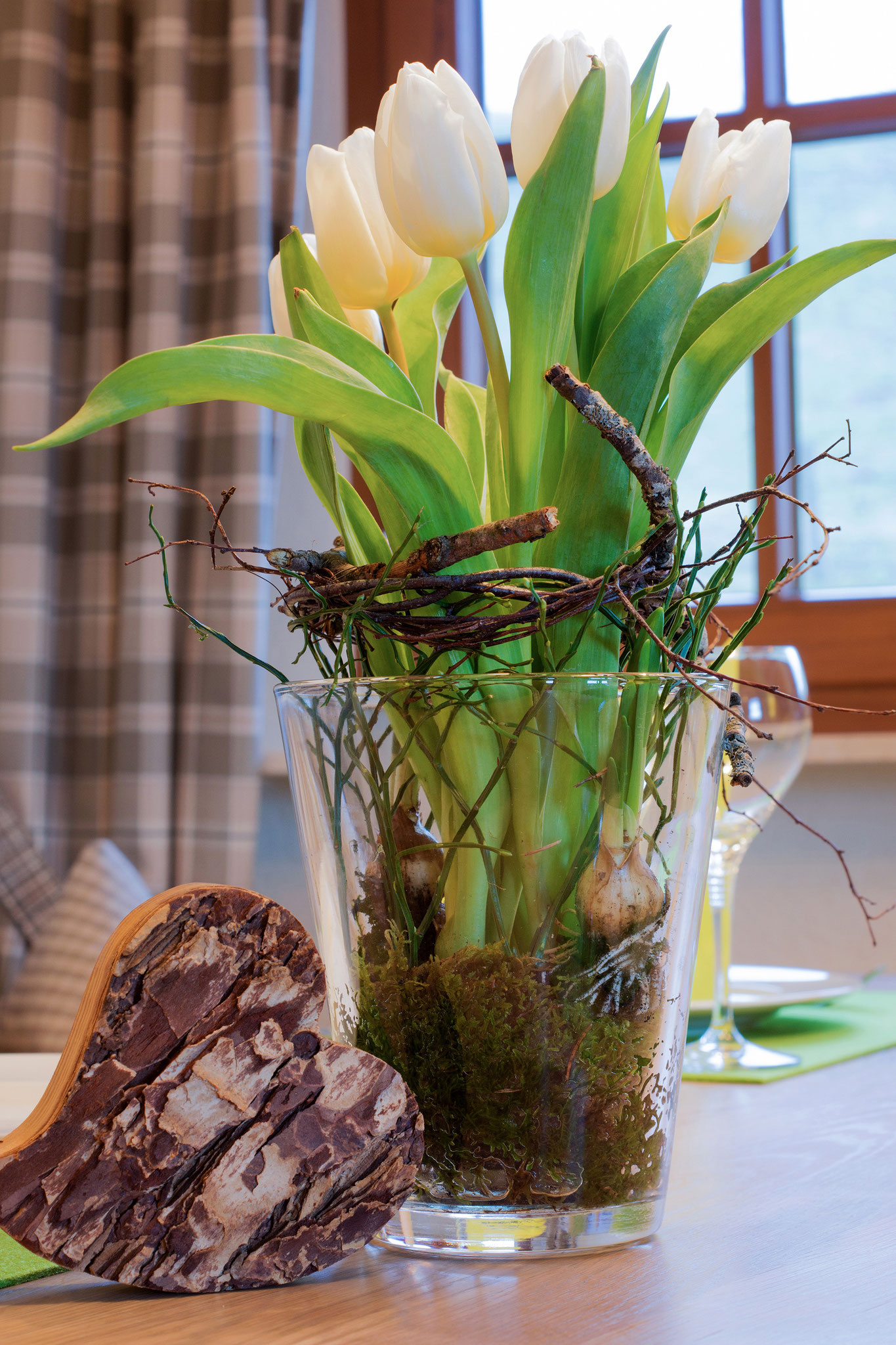 tulpe in durchsichtigem glastopf und holzherz in ferienwohnung