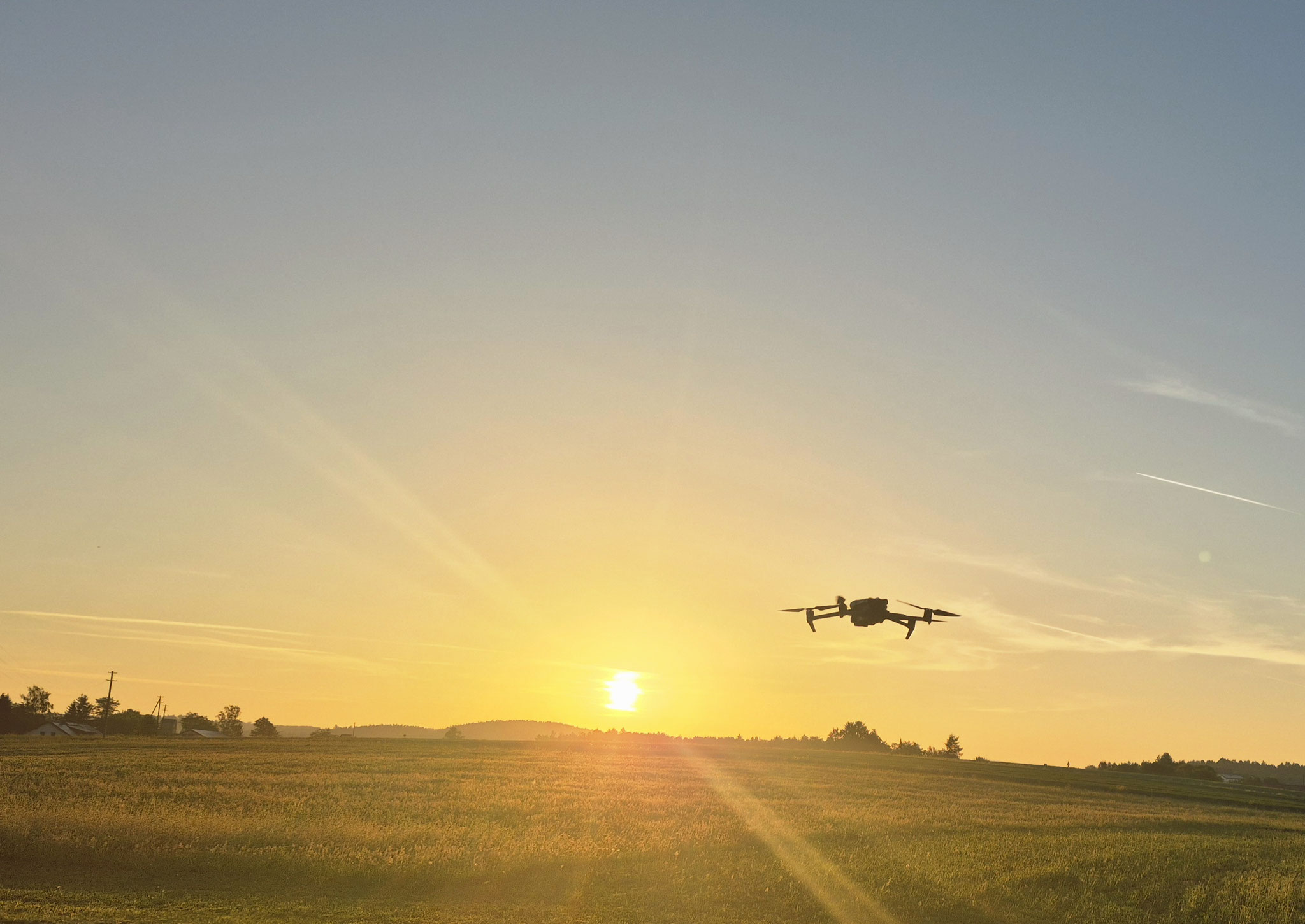 Fliegende Drohne, im Hintergrund aufgehende Sonne