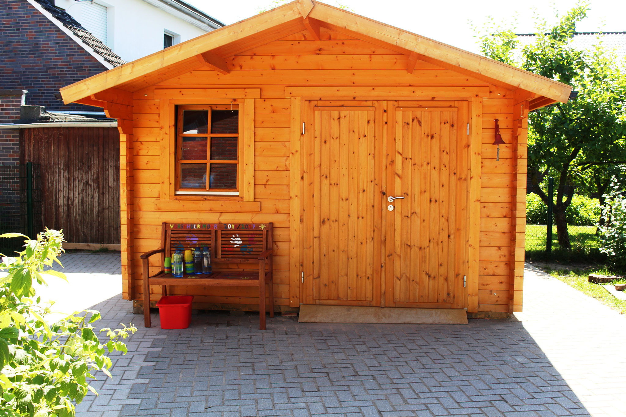 Holzhaus mit Fahrzeugen und Sandspielzeug